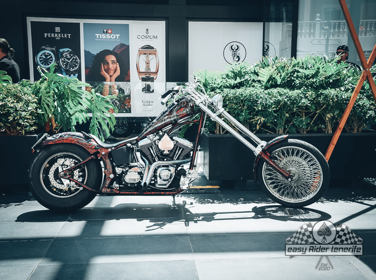 A chopper motorcycle is parked in front of a store.