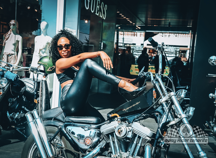 A woman is sitting on a motorcycle in front of a store.