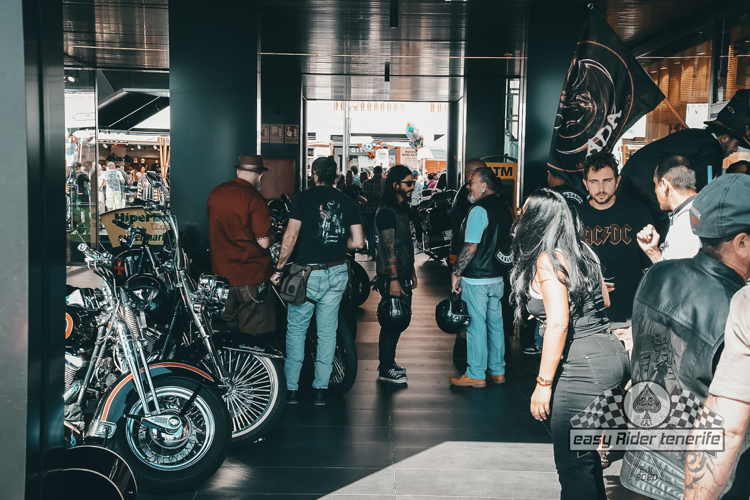 A group of people are standing in a room with motorcycles on display.