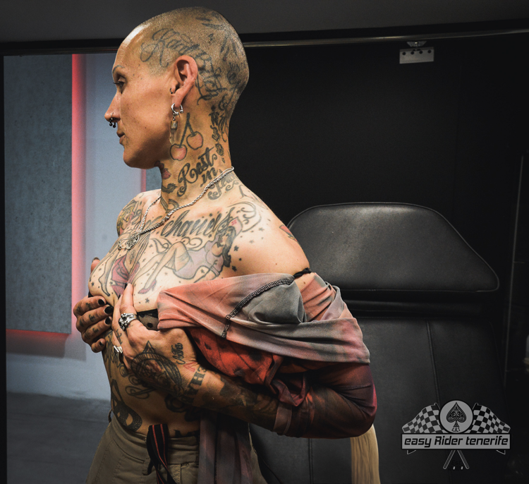 A man with a lot of tattoos on his body is taking off his shirt