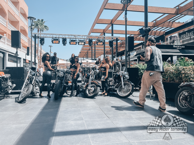 A group of people standing next to motorcycles on a sidewalk.