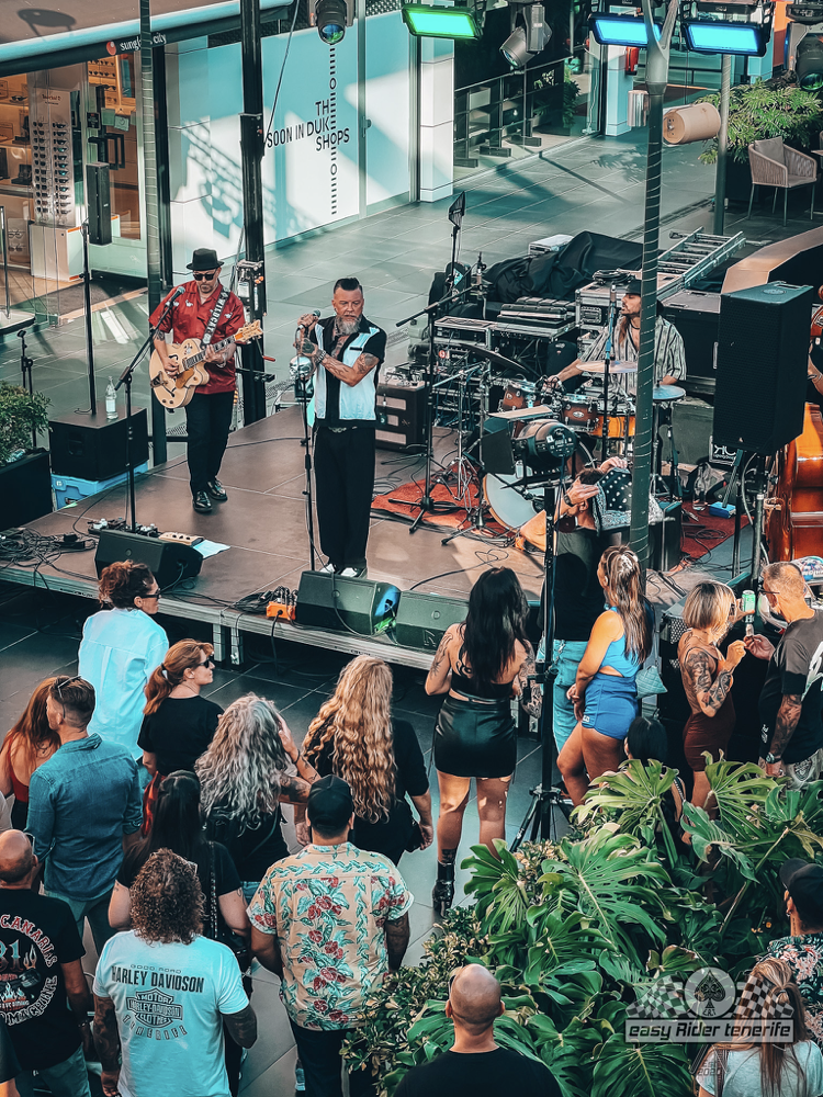 A group of people are standing in front of a stage watching a band perform.