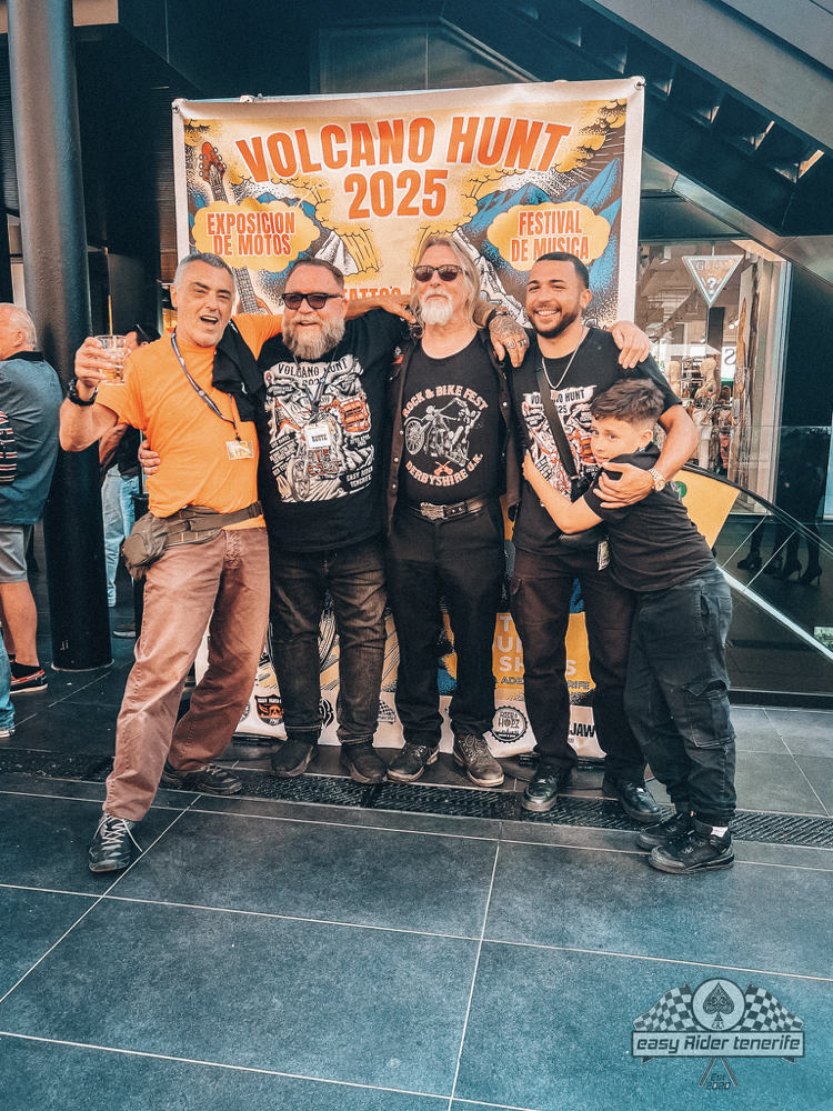 A group of men are posing for a picture in front of a sign that says volcano hunt 2025.