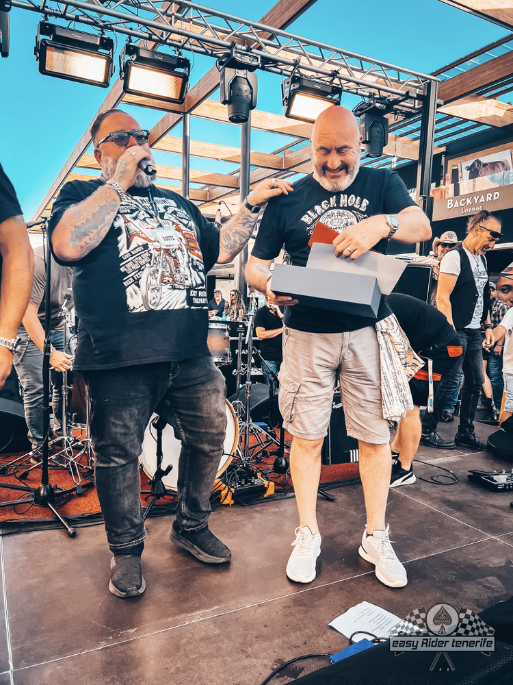 Two men are standing on a stage holding a box.