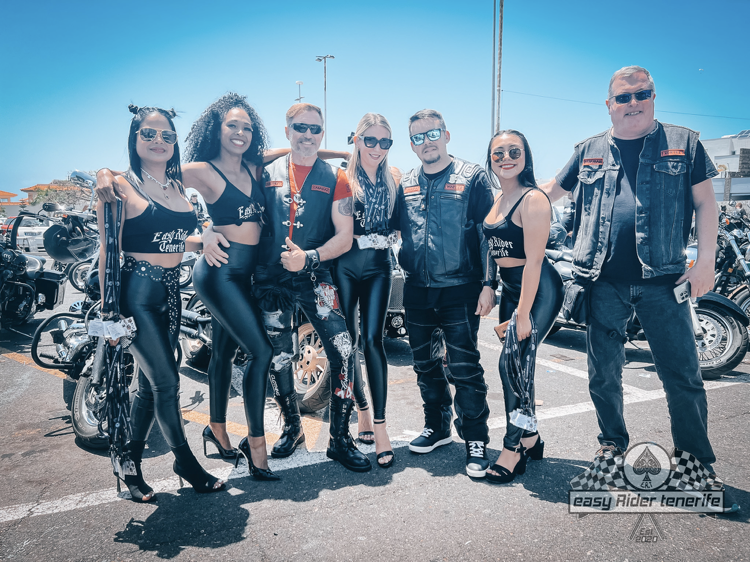 A group of people standing next to motorcycles in a parking lot.