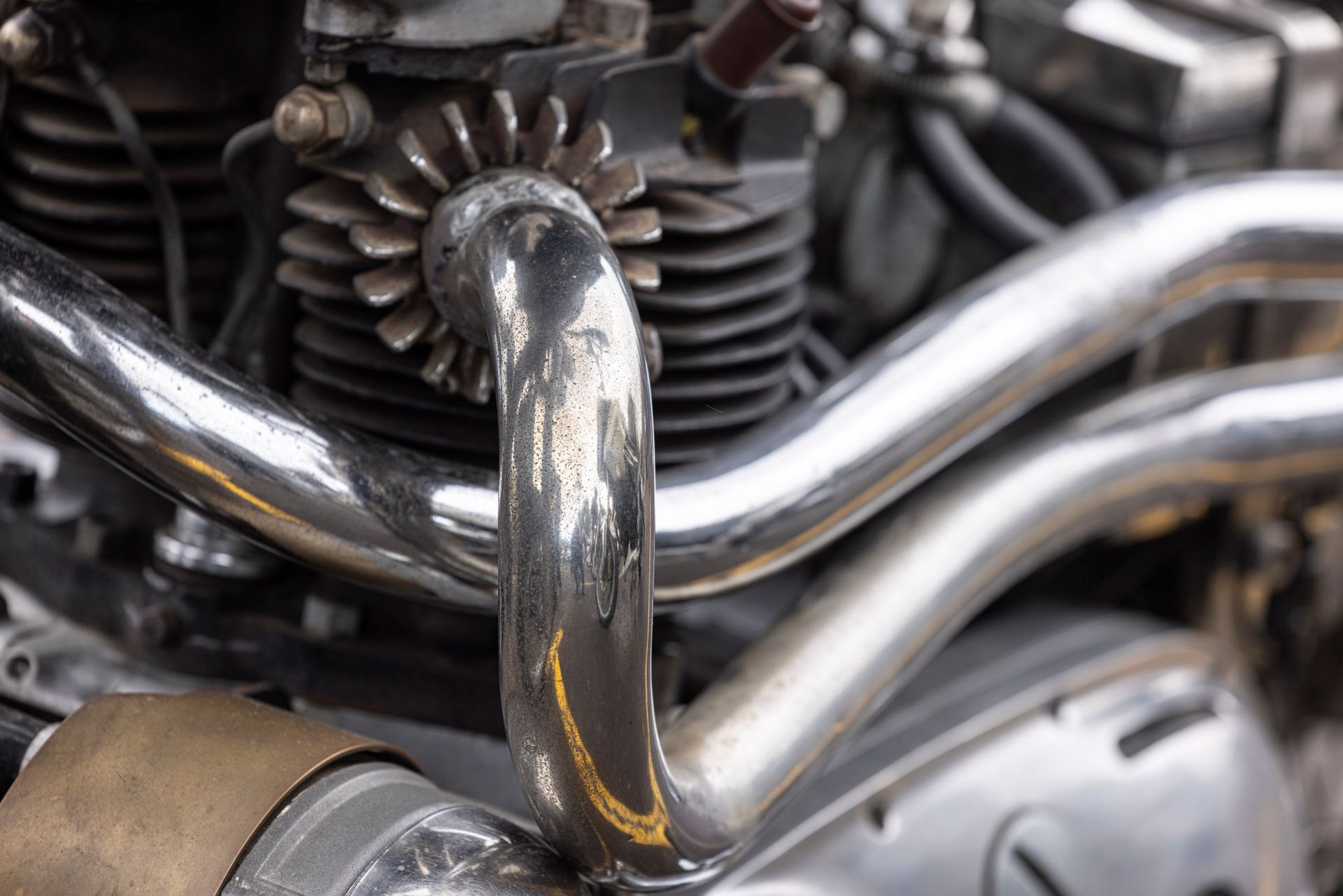 A close up of a motorcycle engine with a stainless steel pipe