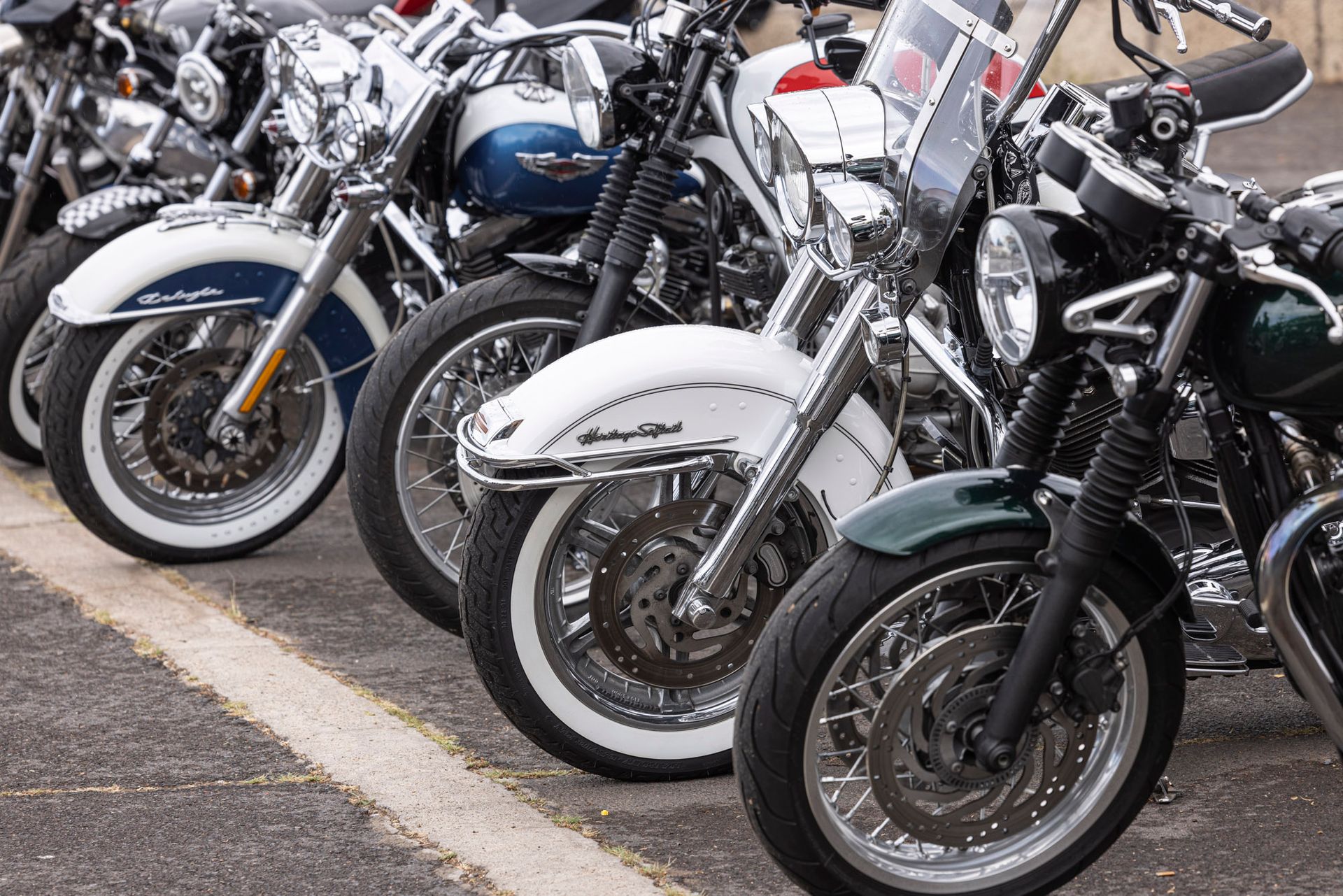 A row of motorcycles are parked in a parking lot.