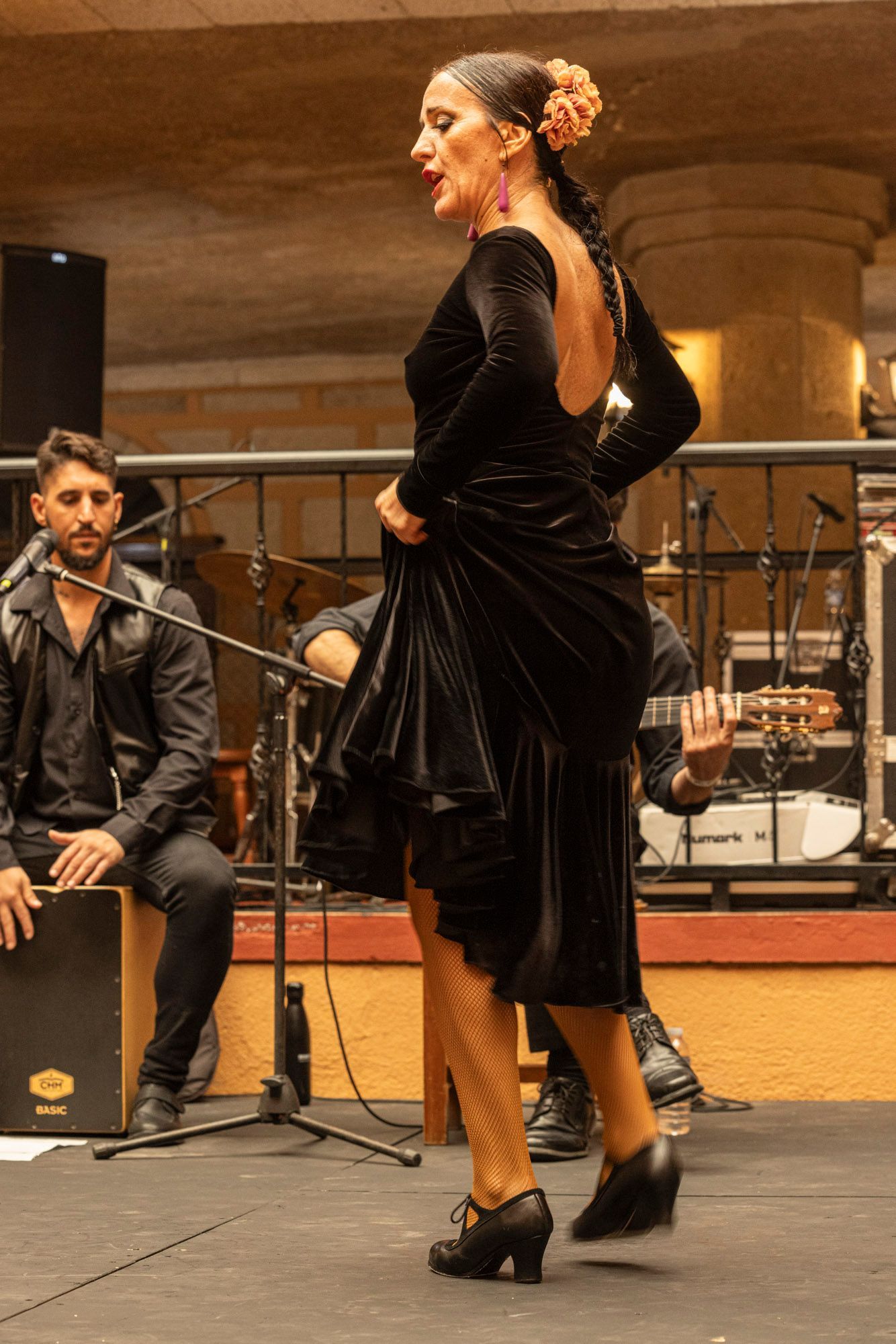 A woman in a black dress is dancing flamenco on a stage.