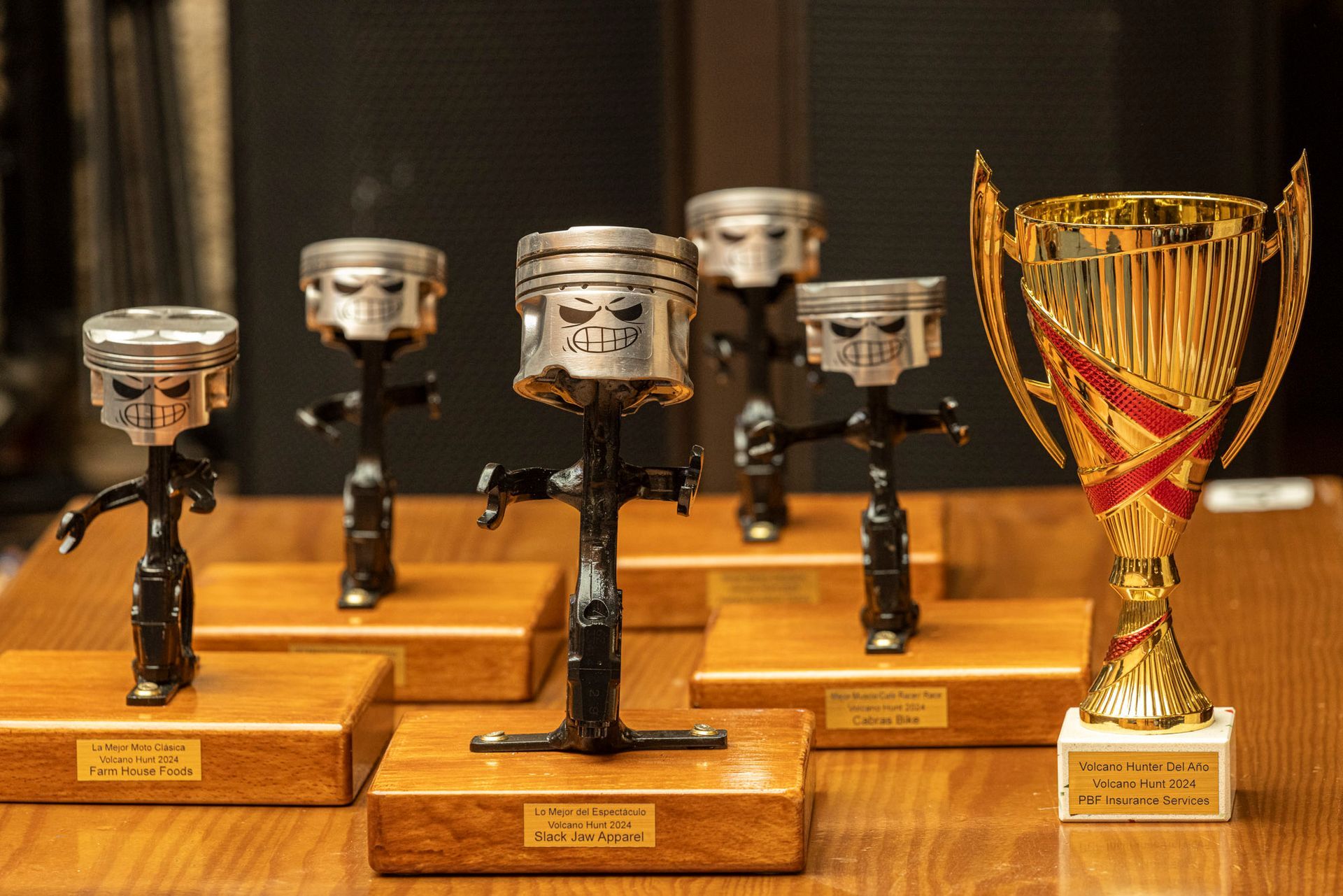 A group of trophies made out of pistons are sitting on a wooden table.