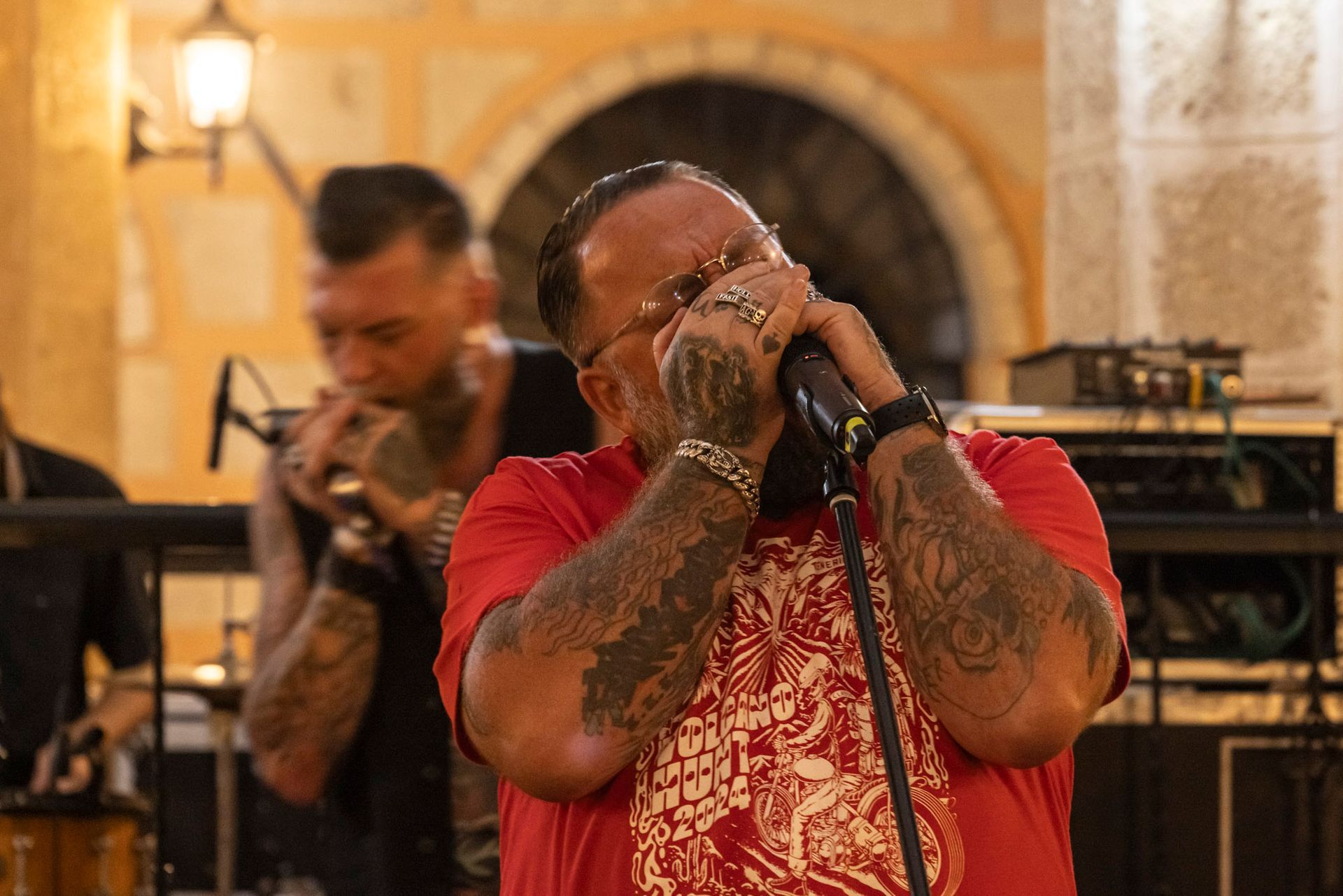 A man in a red shirt is singing into a microphone.