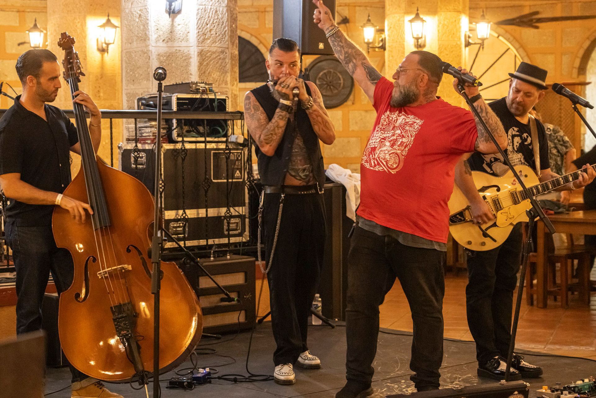 A man in a red shirt is playing a guitar in a band