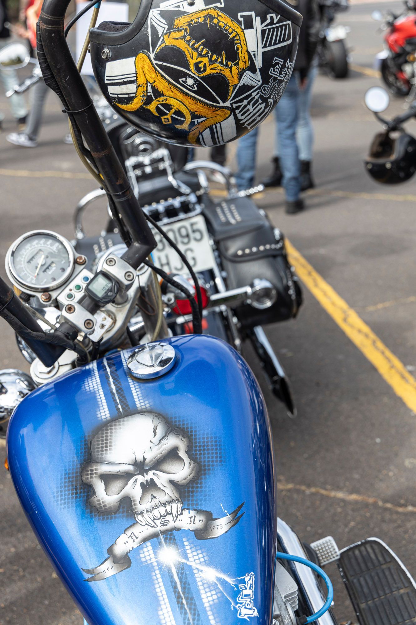 A blue motorcycle with a skull painted on the tank is parked in a parking lot.