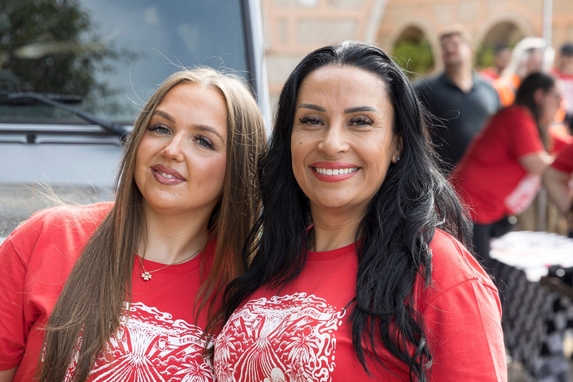 Two women in red shirts are posing for a picture.