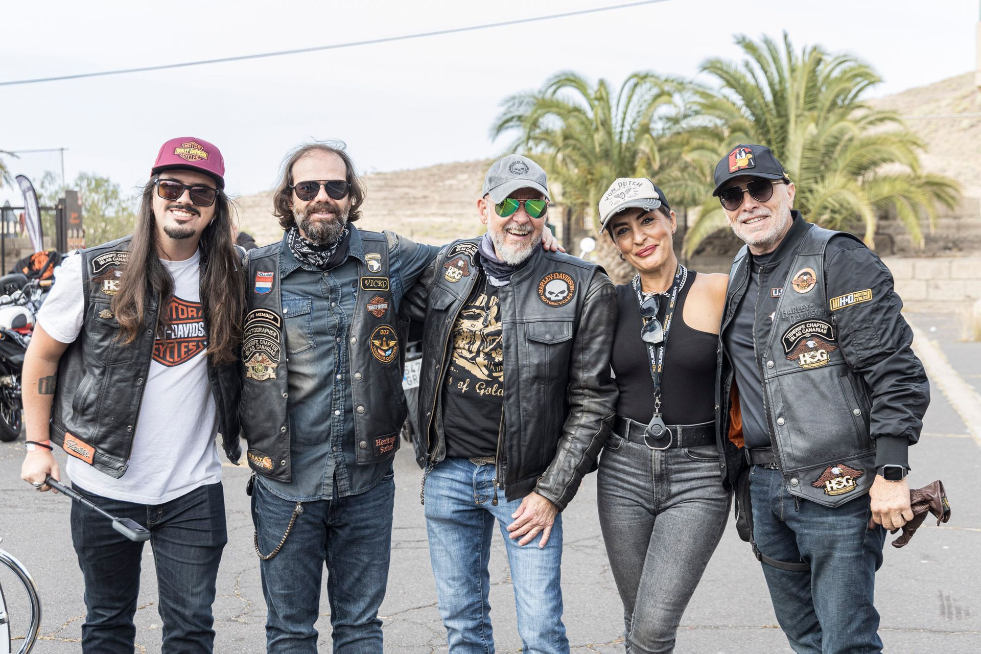 A group of motorcycle riders are posing for a picture on the side of the road.