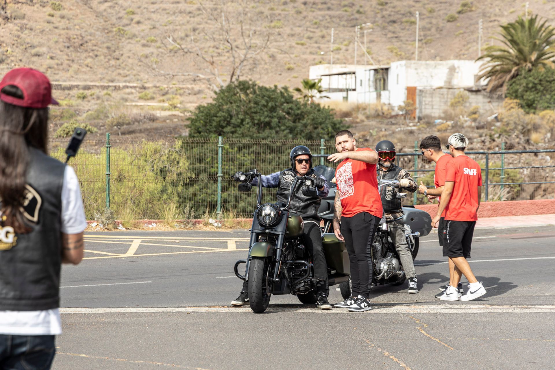 A group of people are standing around a motorcycle on the side of the road.