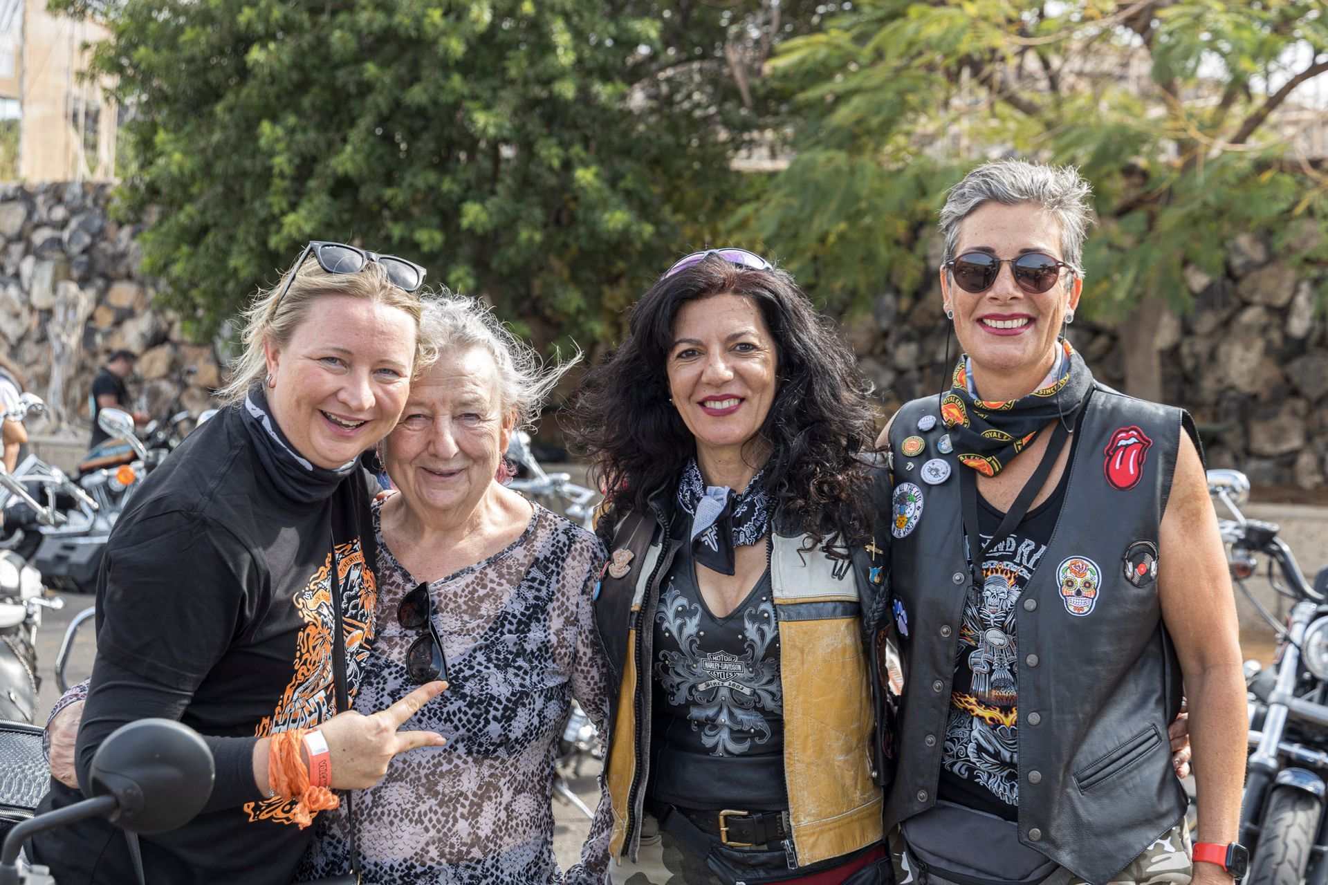 A group of women are posing for a picture in front of motorcycles.