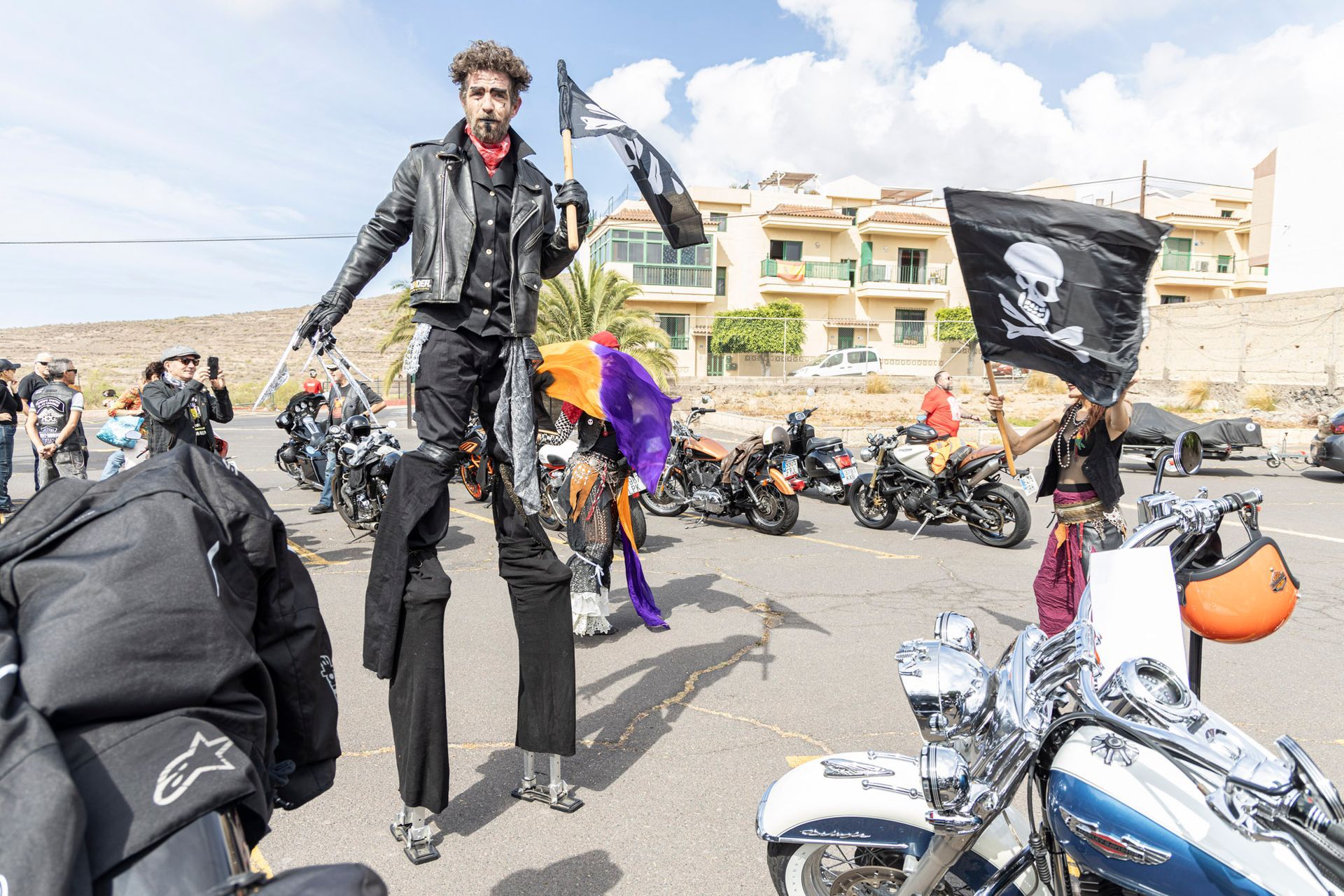 A man on stilts is standing in front of a row of motorcycles.