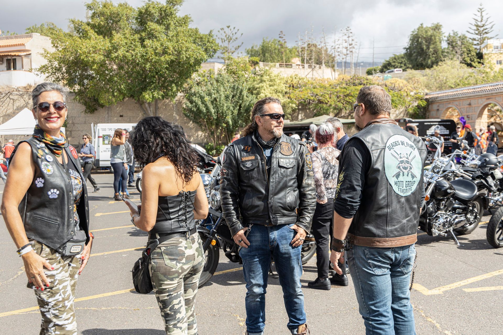 A group of people standing on a street next to motorcycles.