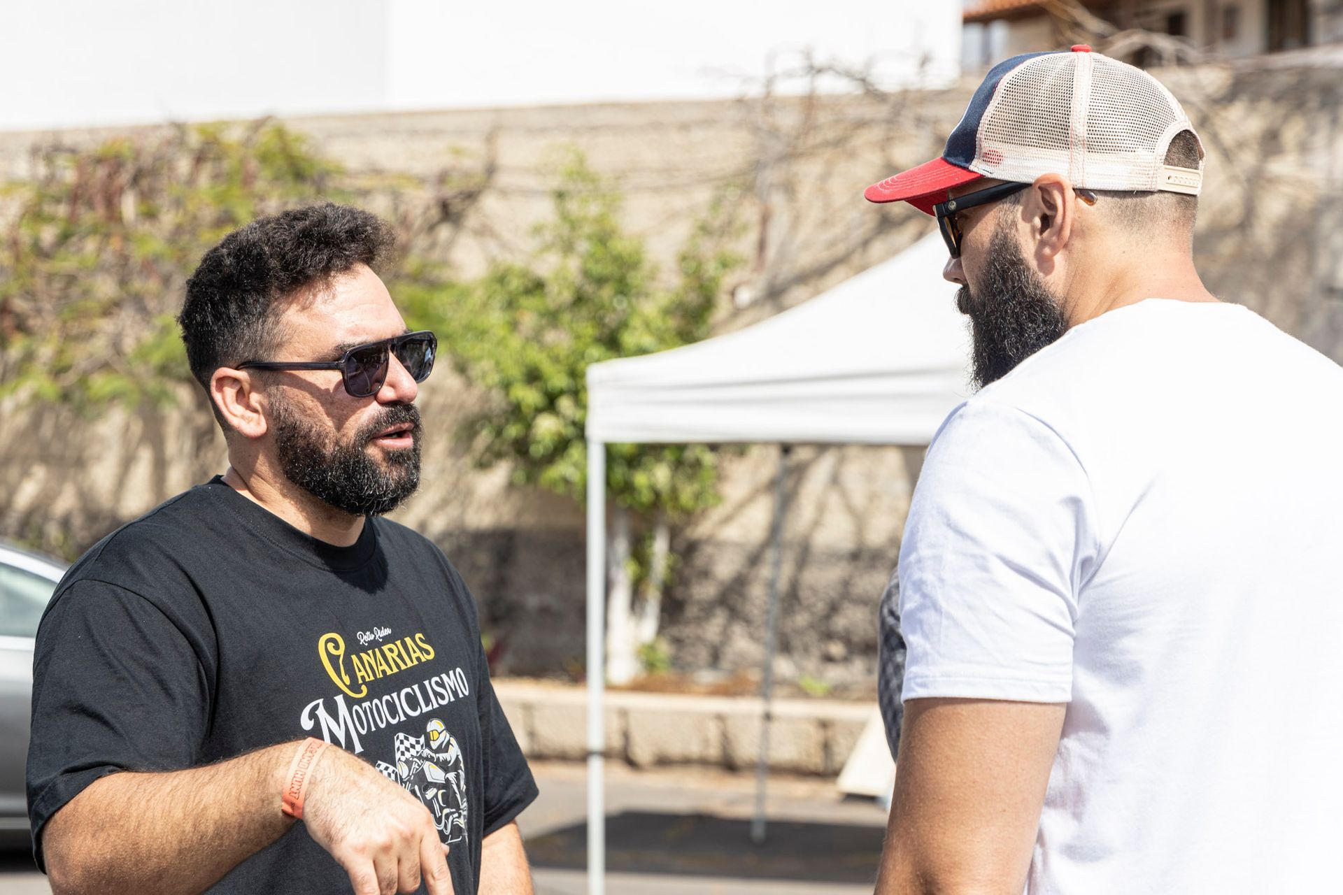Two men are standing next to each other and talking in front of a tent.