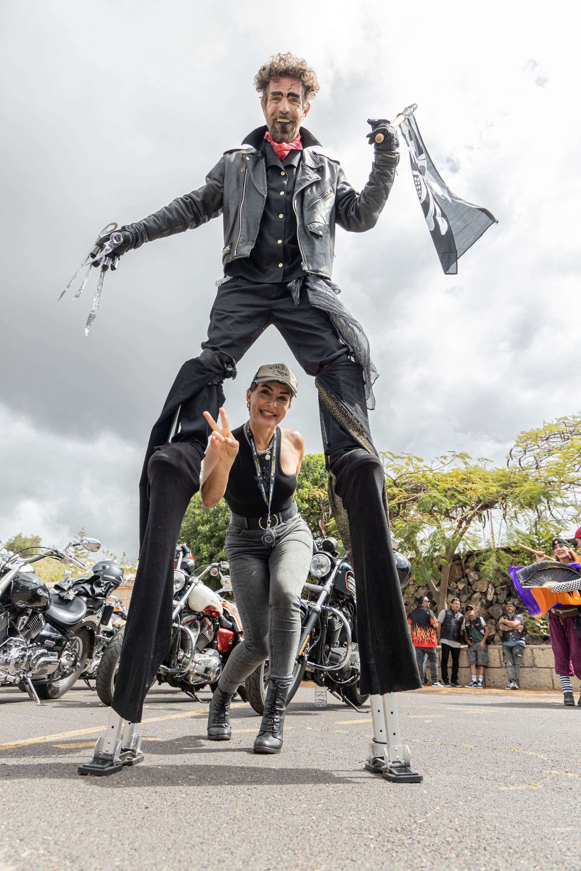 A man is standing on stilts next to a woman.
