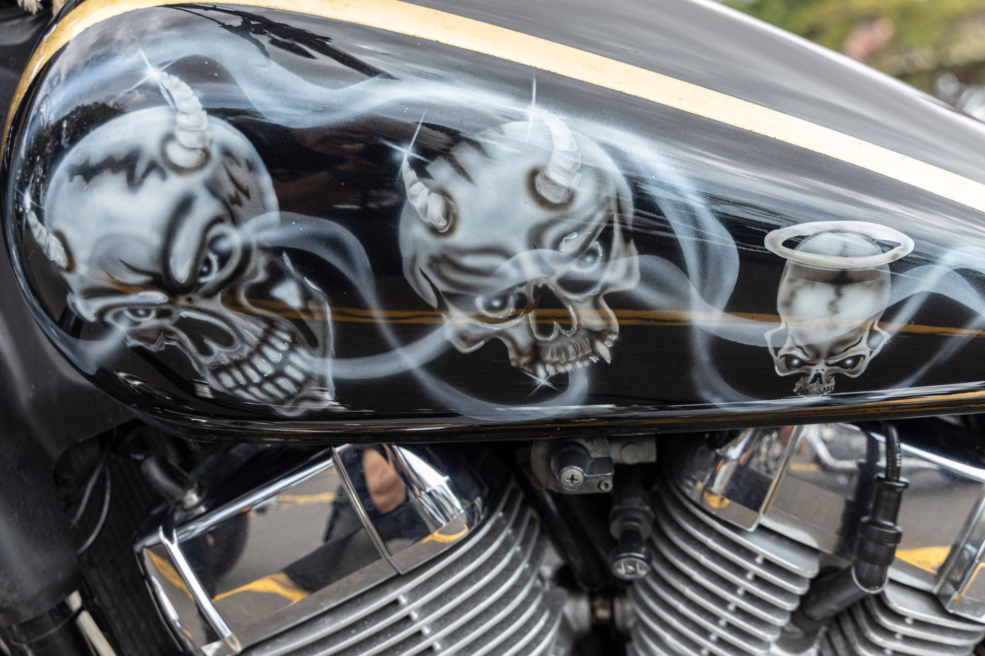 A close up of a motorcycle tank with skulls painted on it.