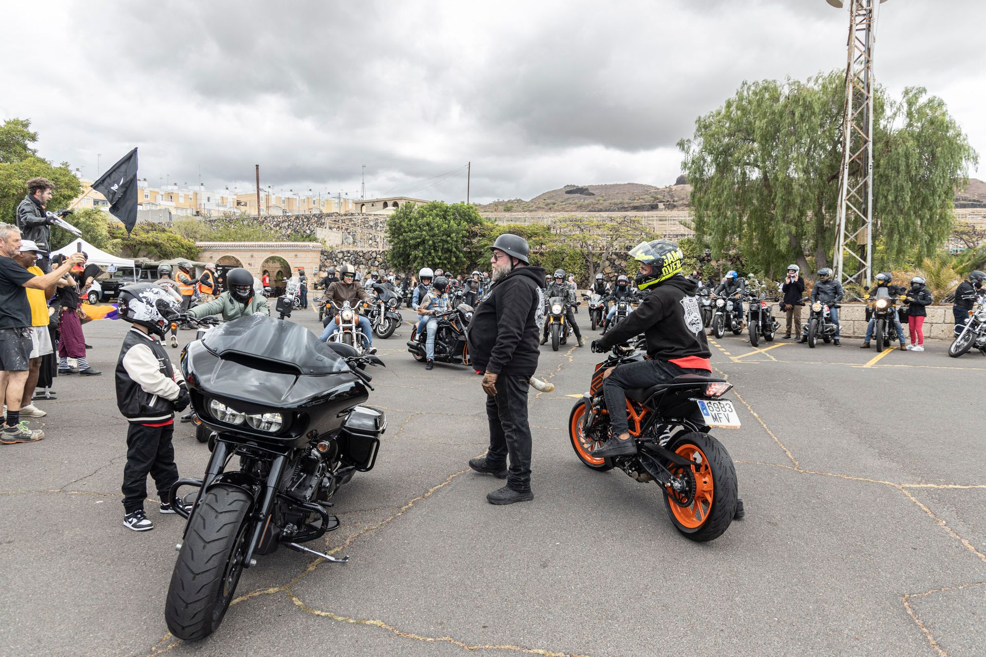 A group of people are standing around motorcycles in a parking lot.