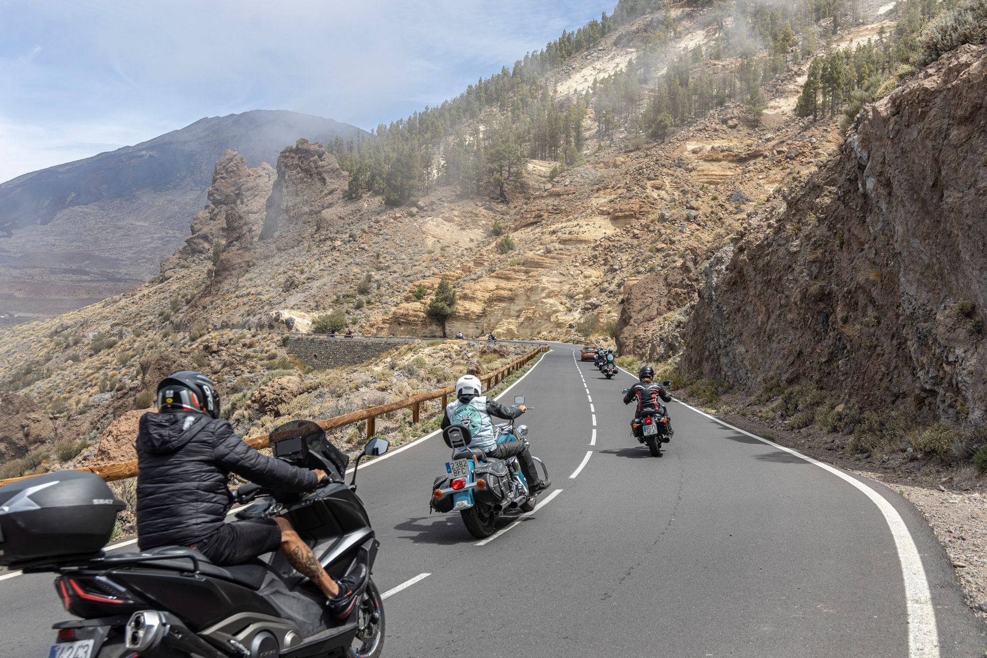 A group of people are riding motorcycles down a mountain road.
