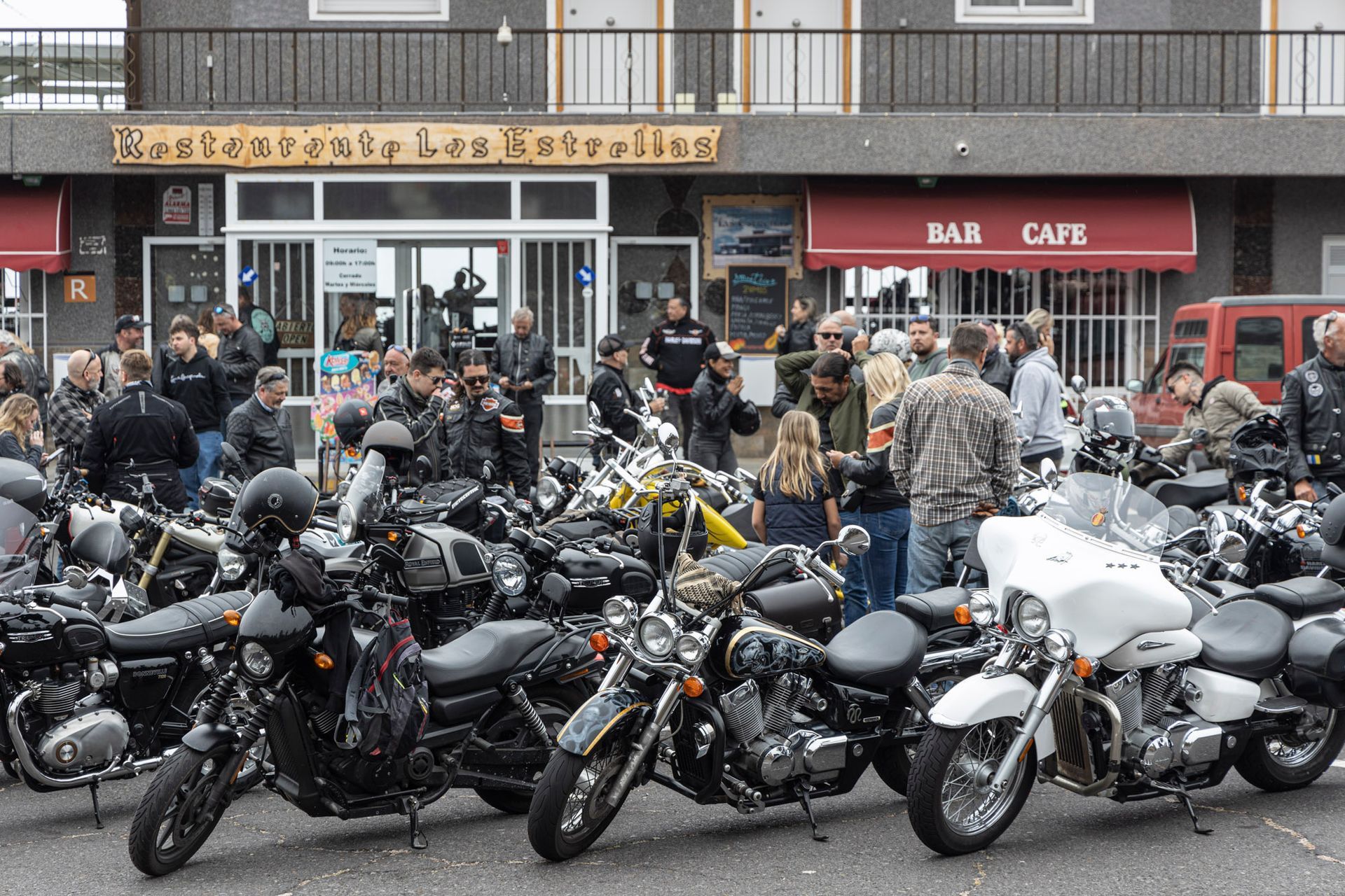 A bunch of motorcycles are parked in front of a cafe