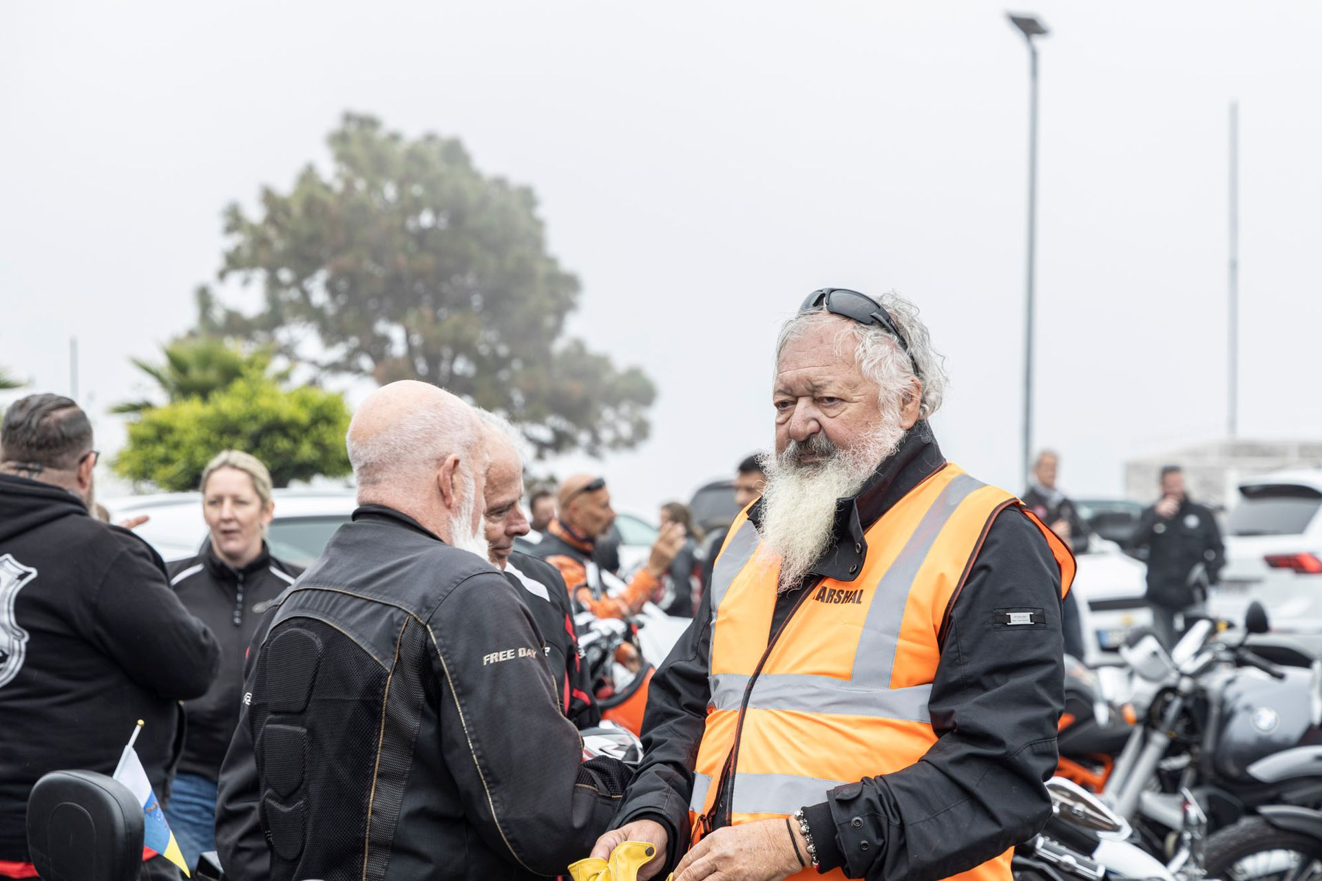 A group of motorcycle riders are shaking hands in a parking lot.