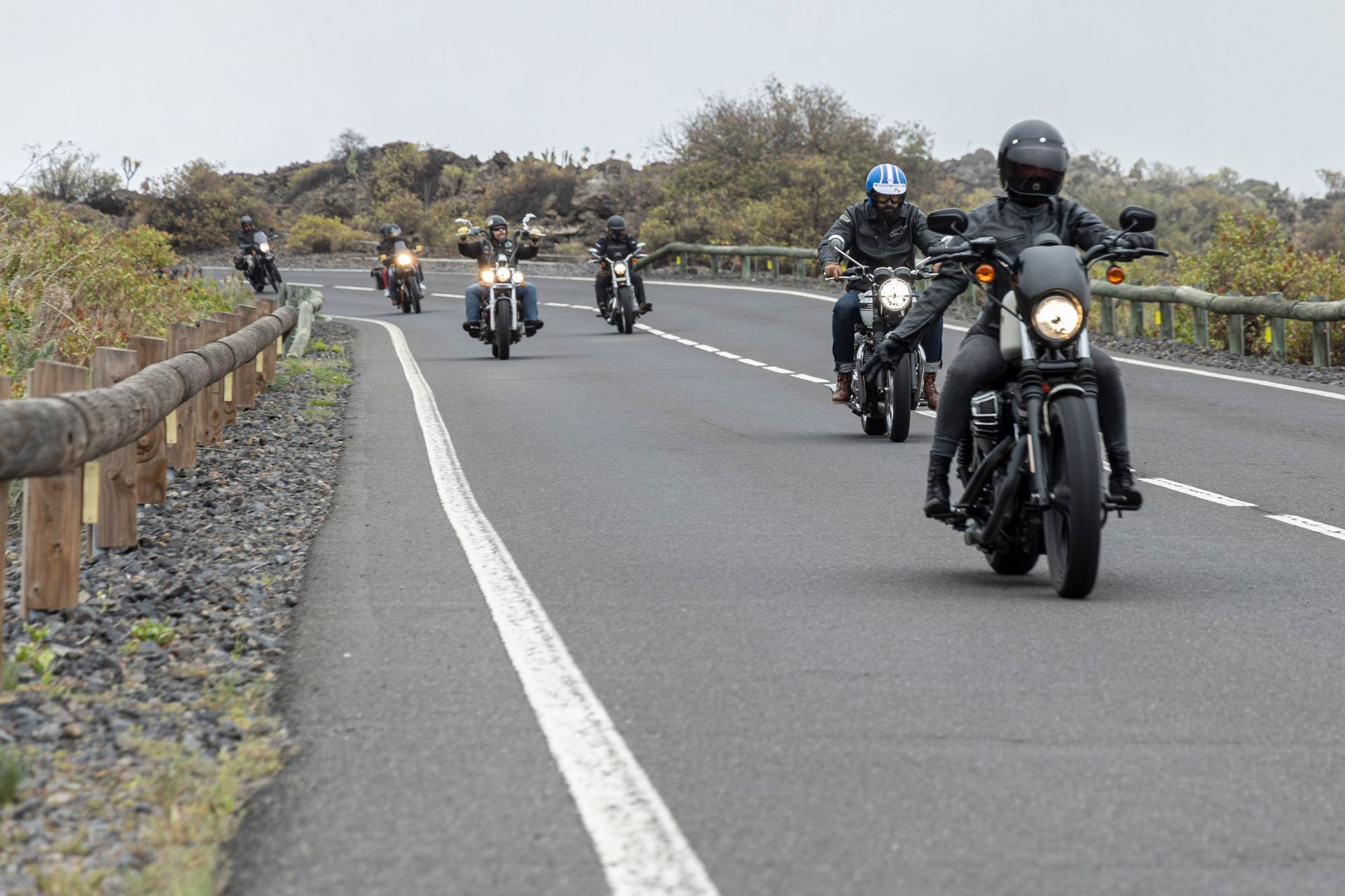 A group of people are riding motorcycles down a road