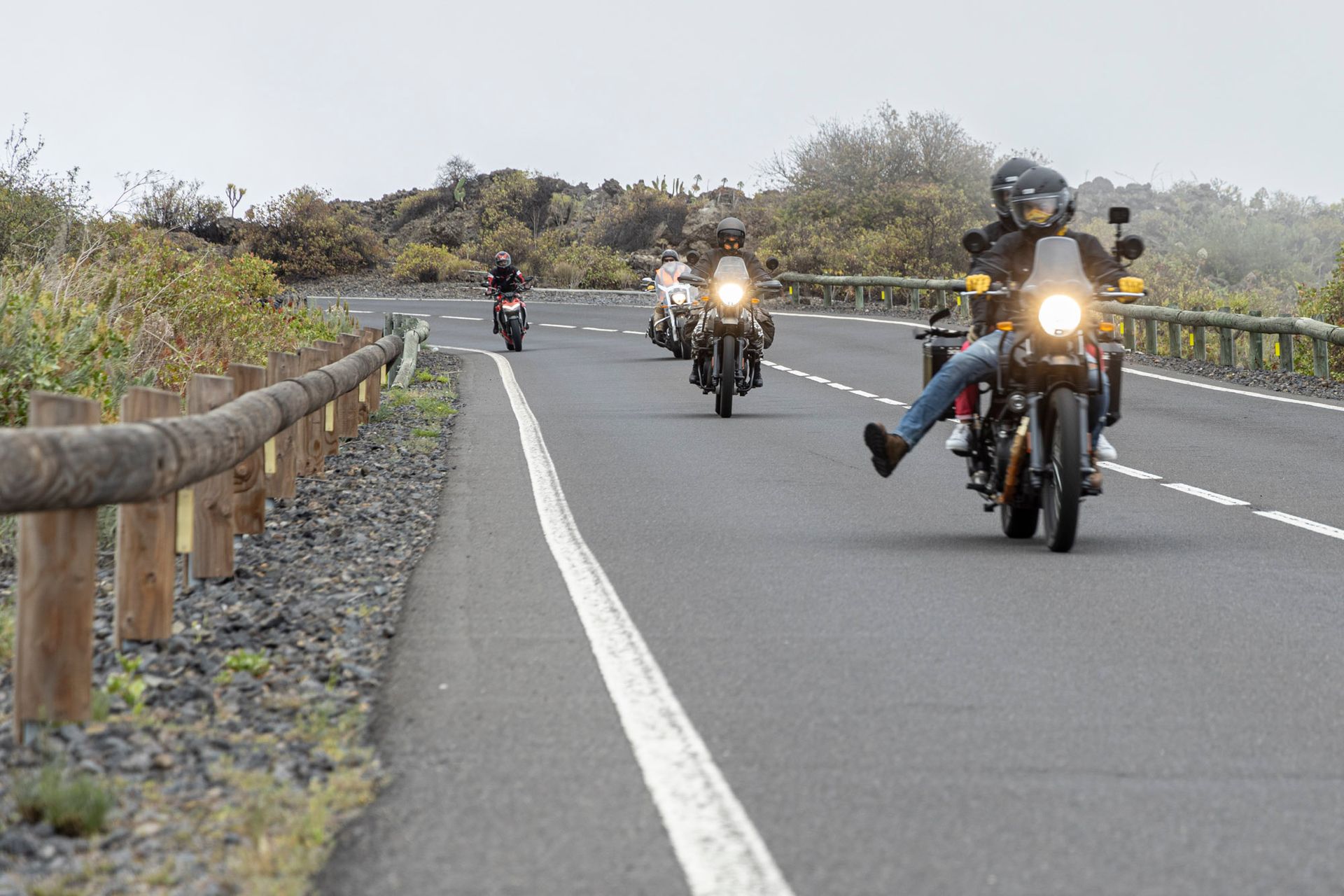 A group of people are riding motorcycles down a road.
