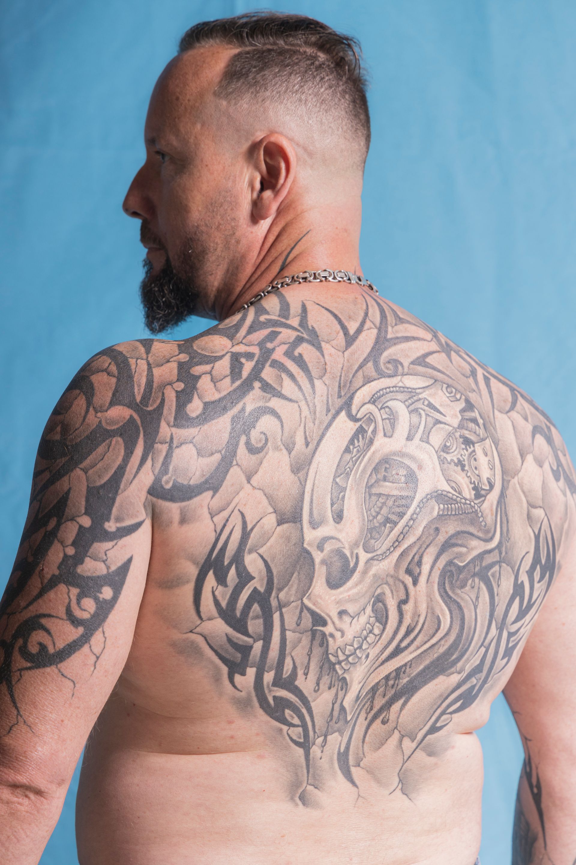 A shirtless man with a lot of tattoos on his back.