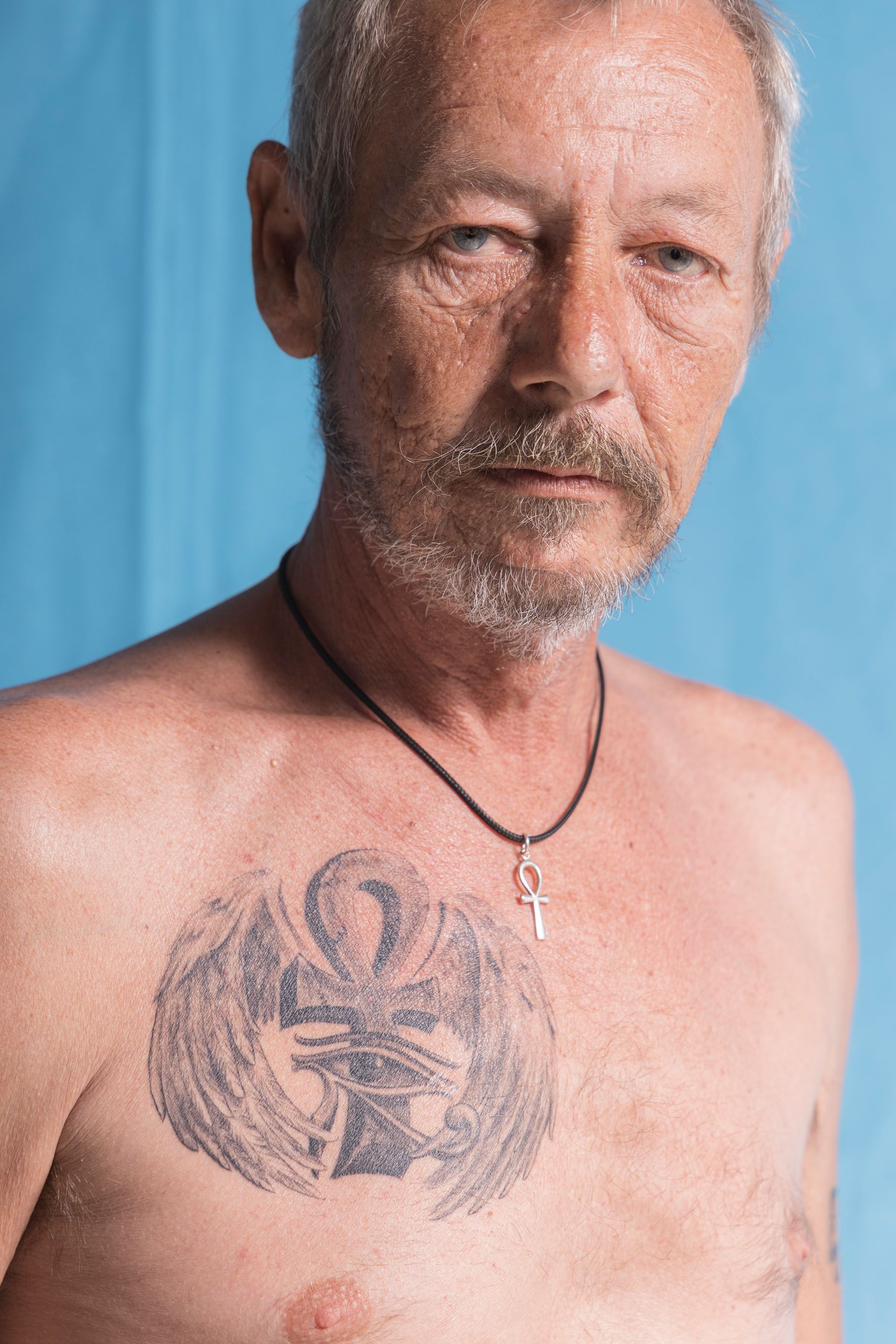 A shirtless man with a tattoo on his chest.