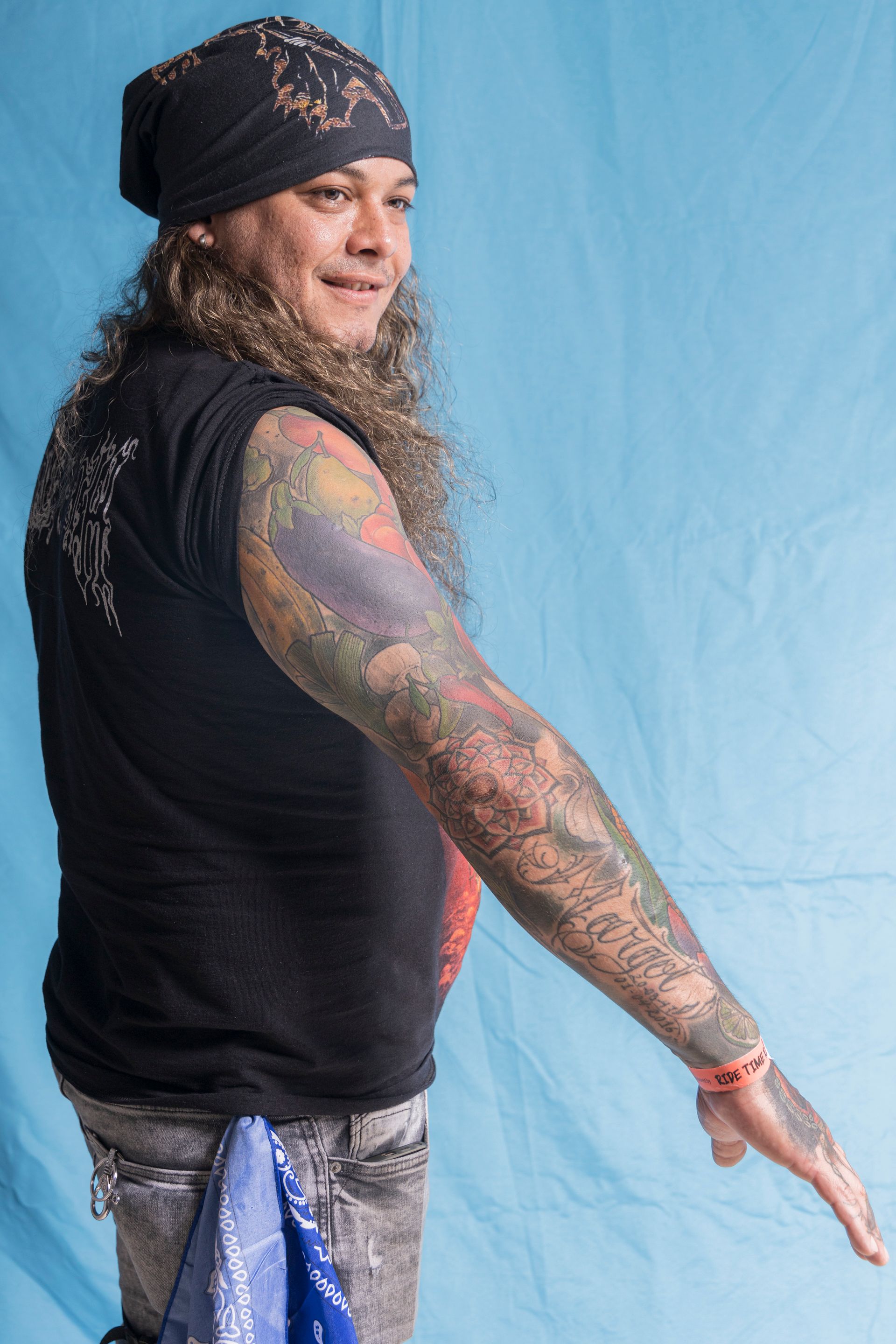 A man with a bandana on his head has a lot of tattoos on his arms