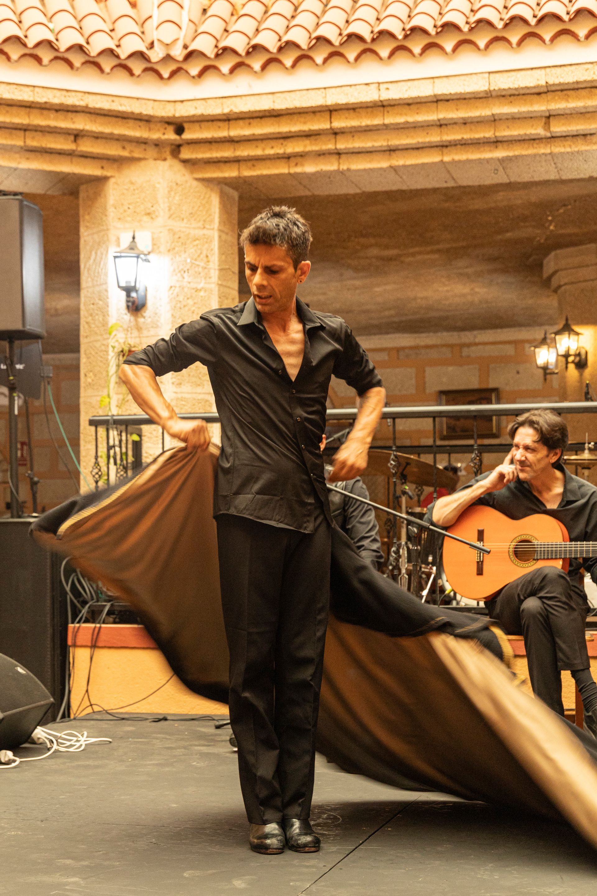 A man in a black shirt is dancing in front of two men playing guitars