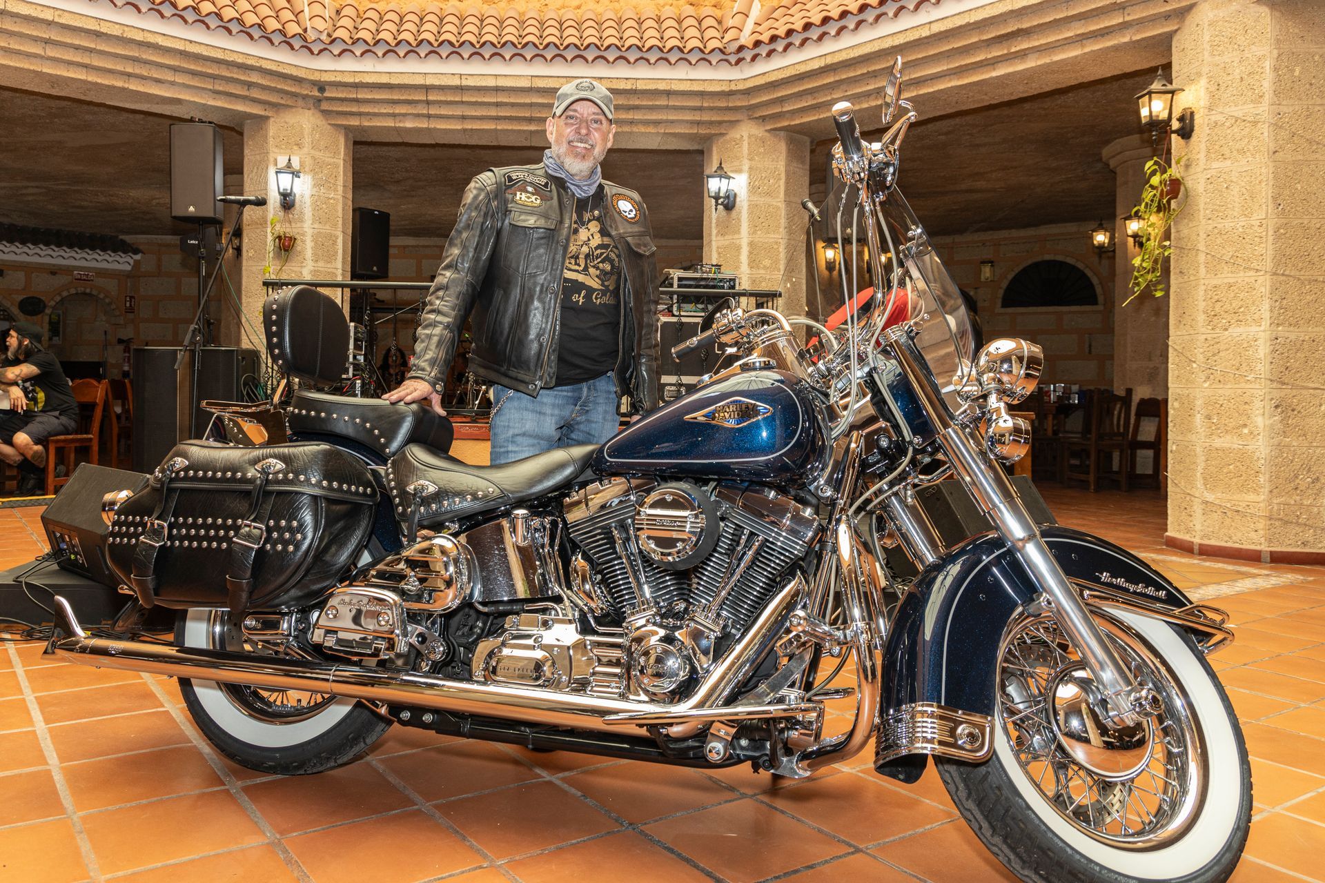 A man is standing next to a harley davidson motorcycle in a room.