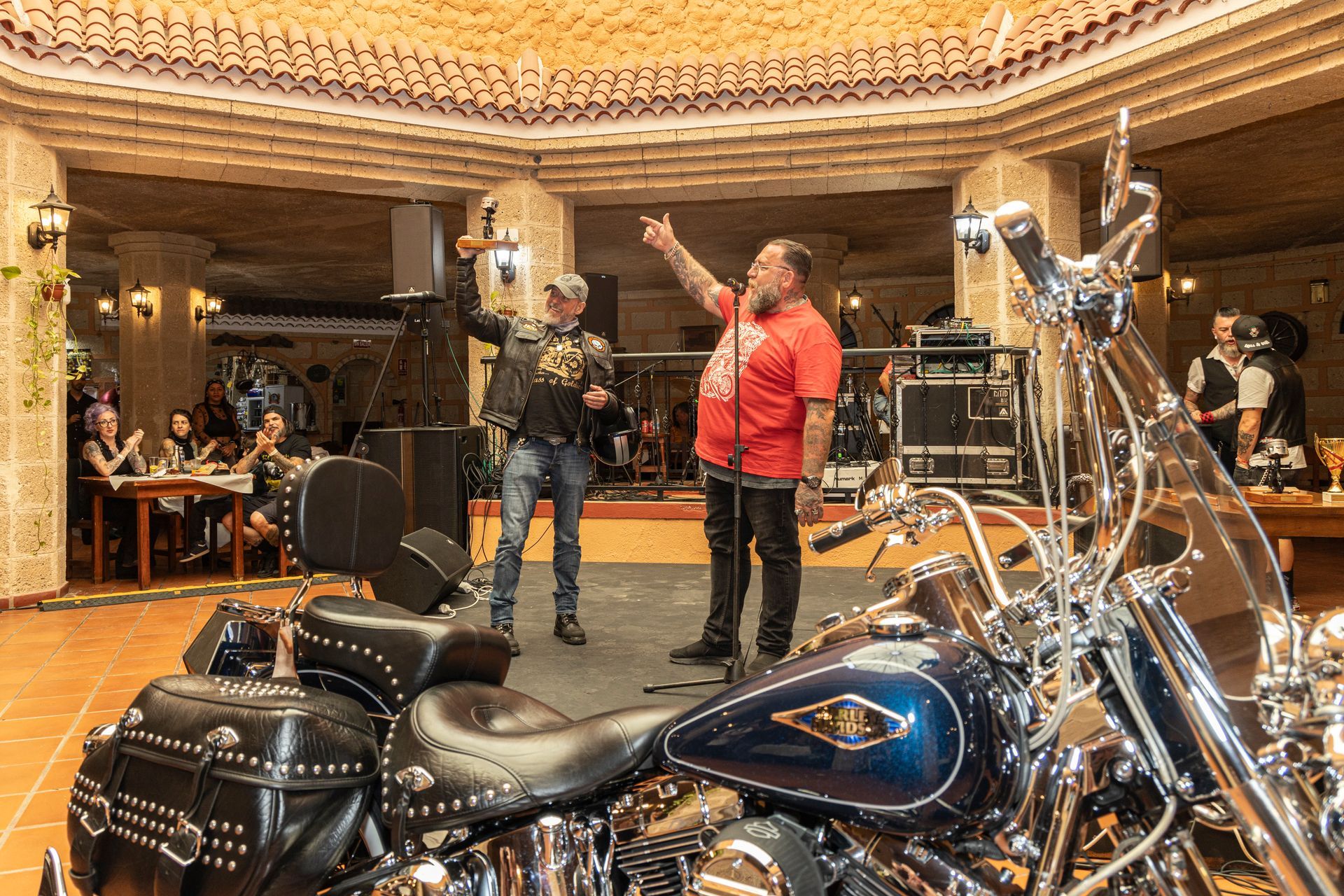Two men are standing next to a motorcycle in a room.