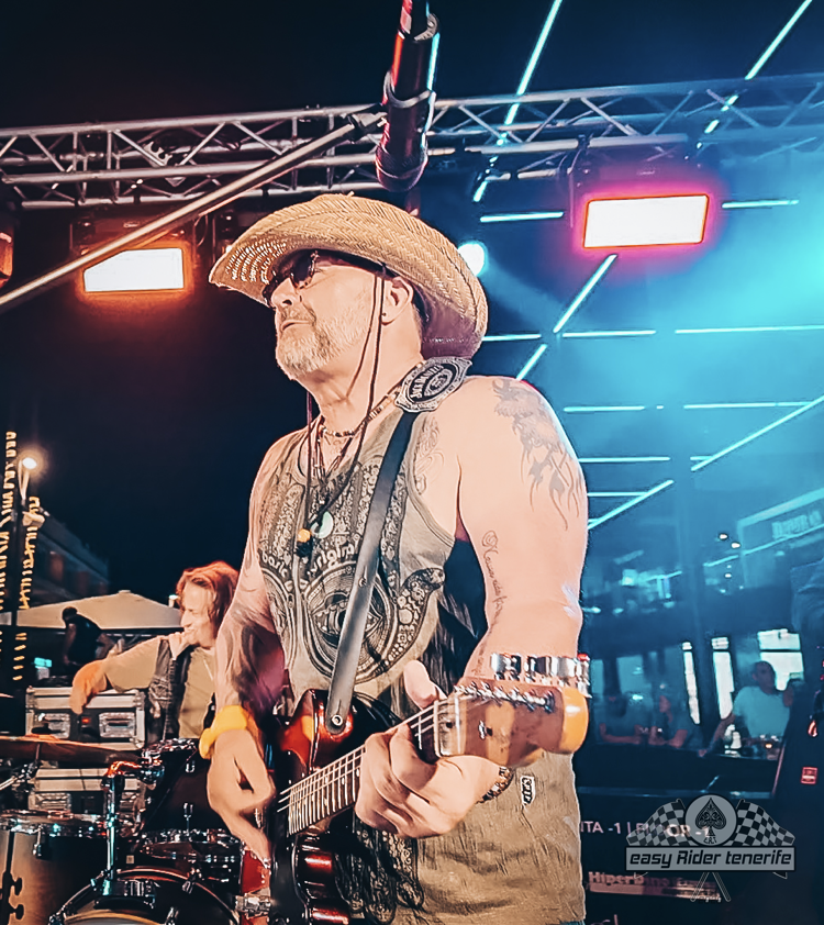 A man in a cowboy hat is playing a guitar on stage