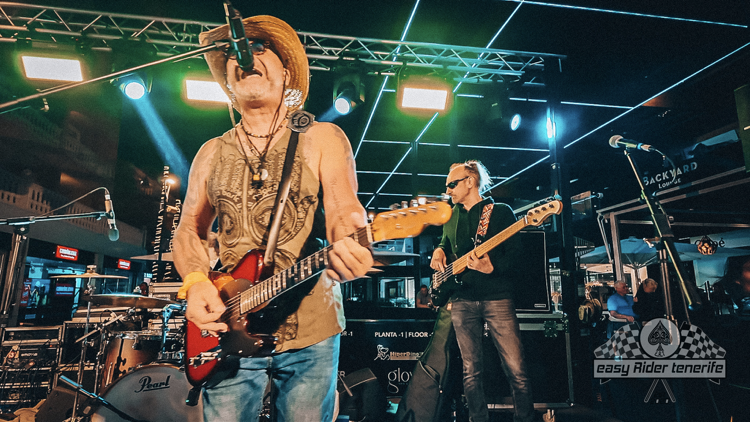 A man in a cowboy hat is playing a guitar on stage.