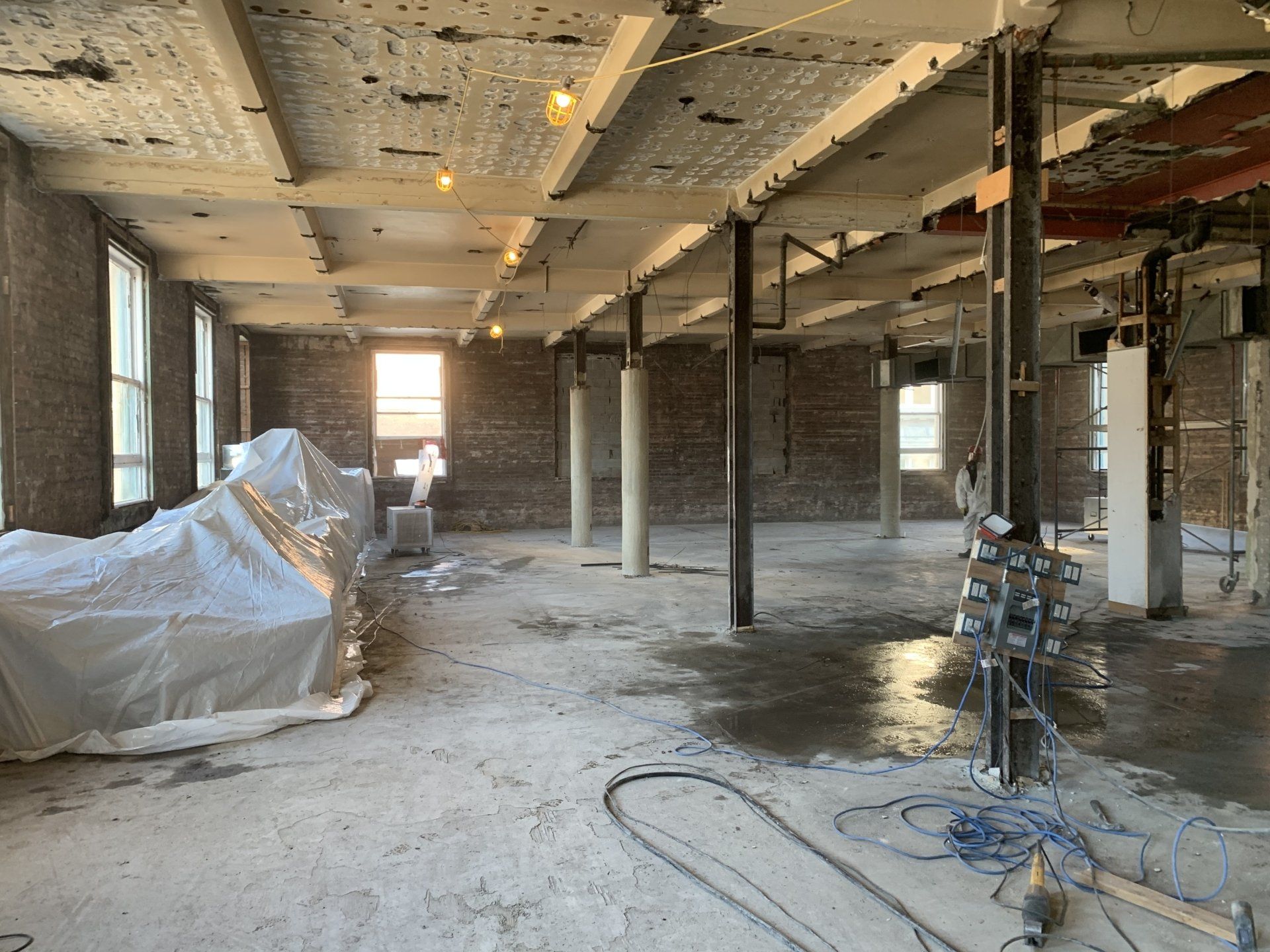 Intérieur d'un bâtiment en construction, montrant des poutres en béton, des murs en briques et des colonnes en acier.