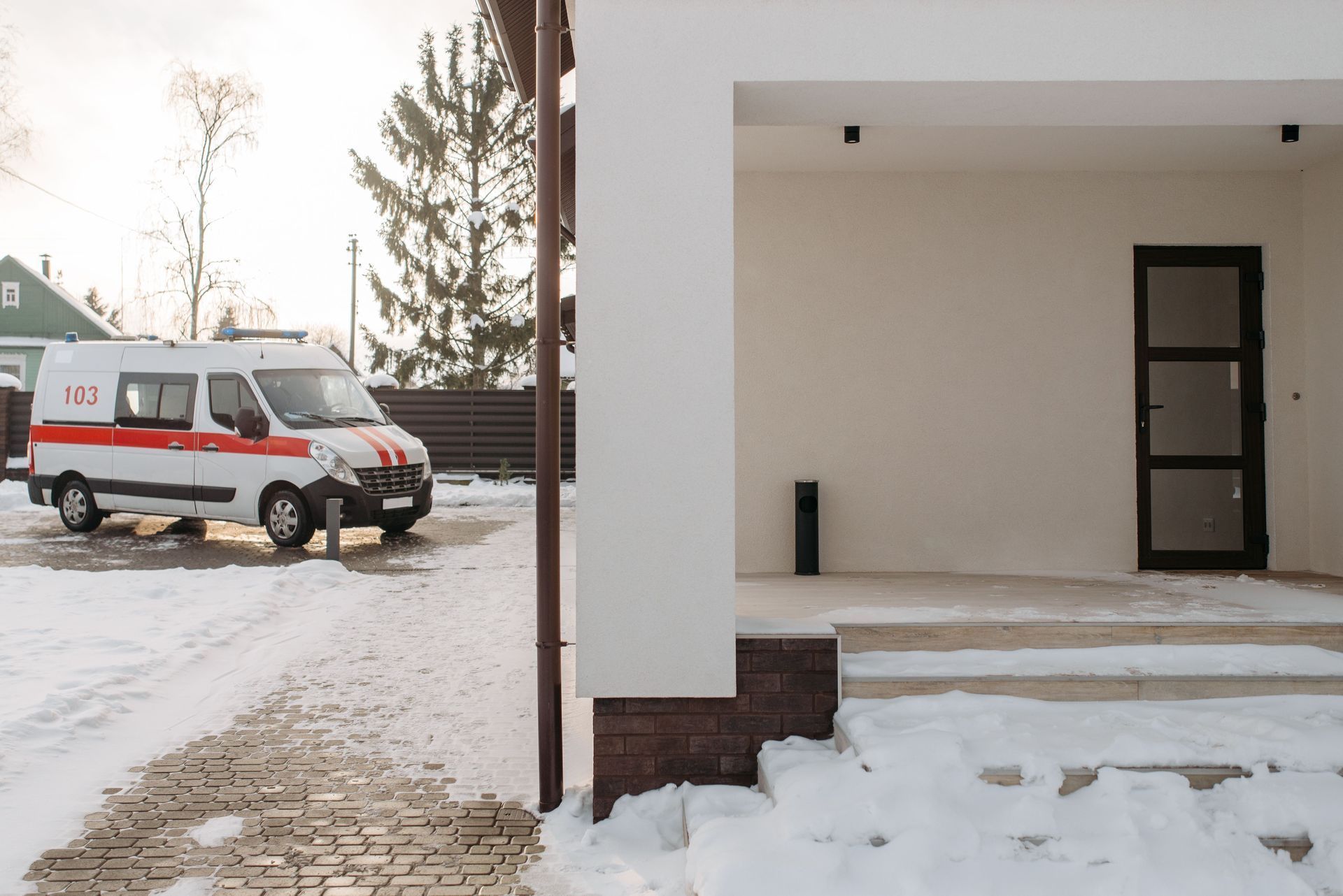 White van parked on a snowy driveway beside a beige building entrance
