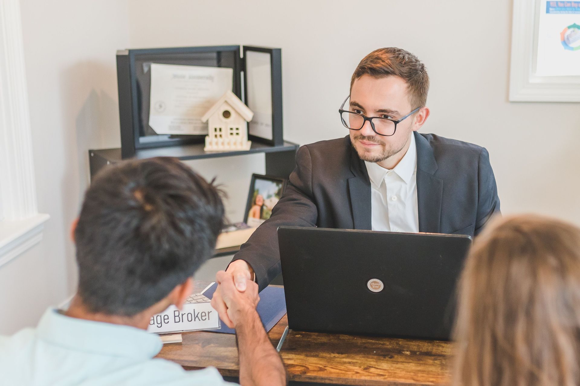 Meeting with a man behind a laptop, speaking to two seated clients in a bright office