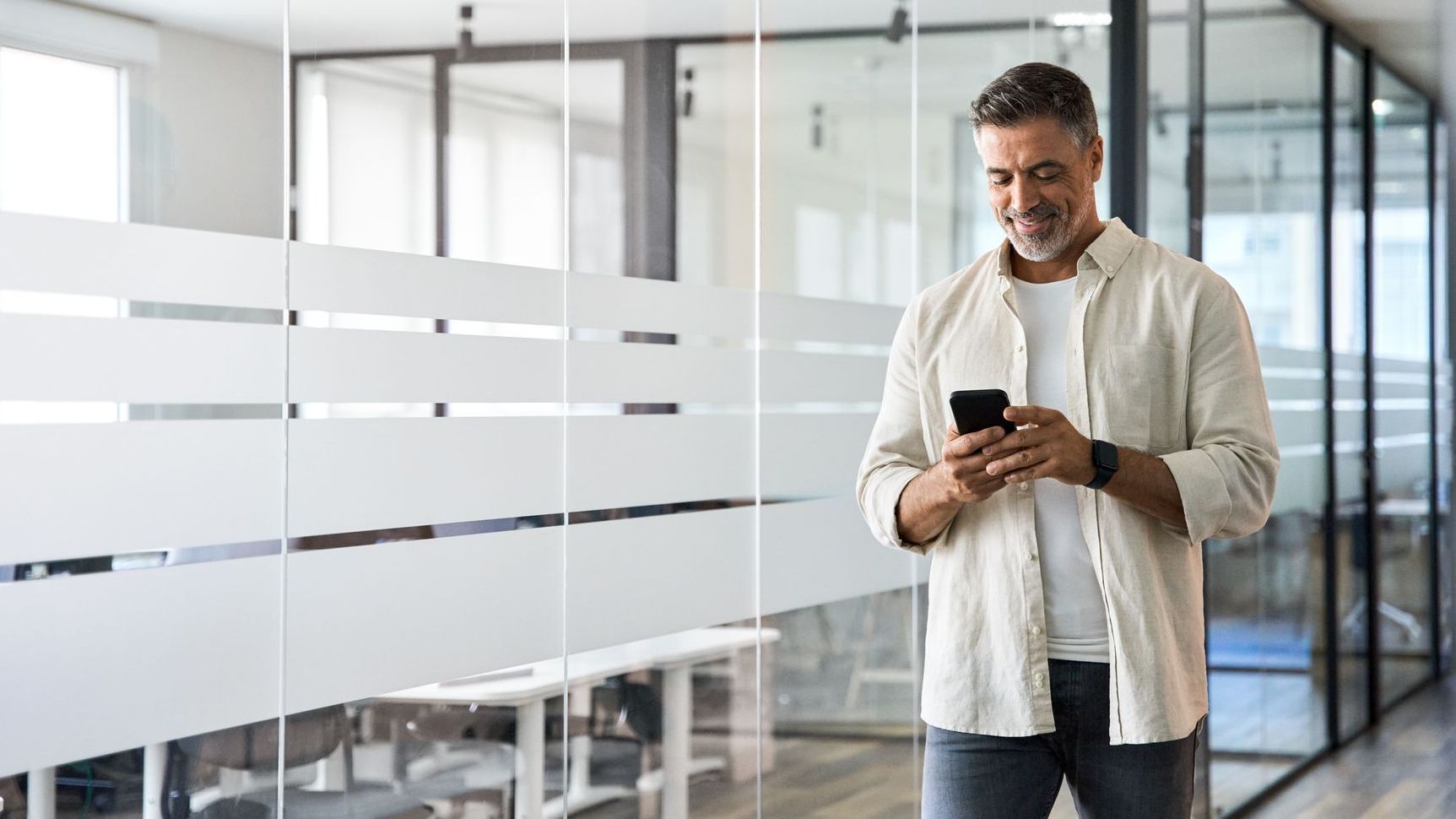 businessman walking with smartphone in office.
