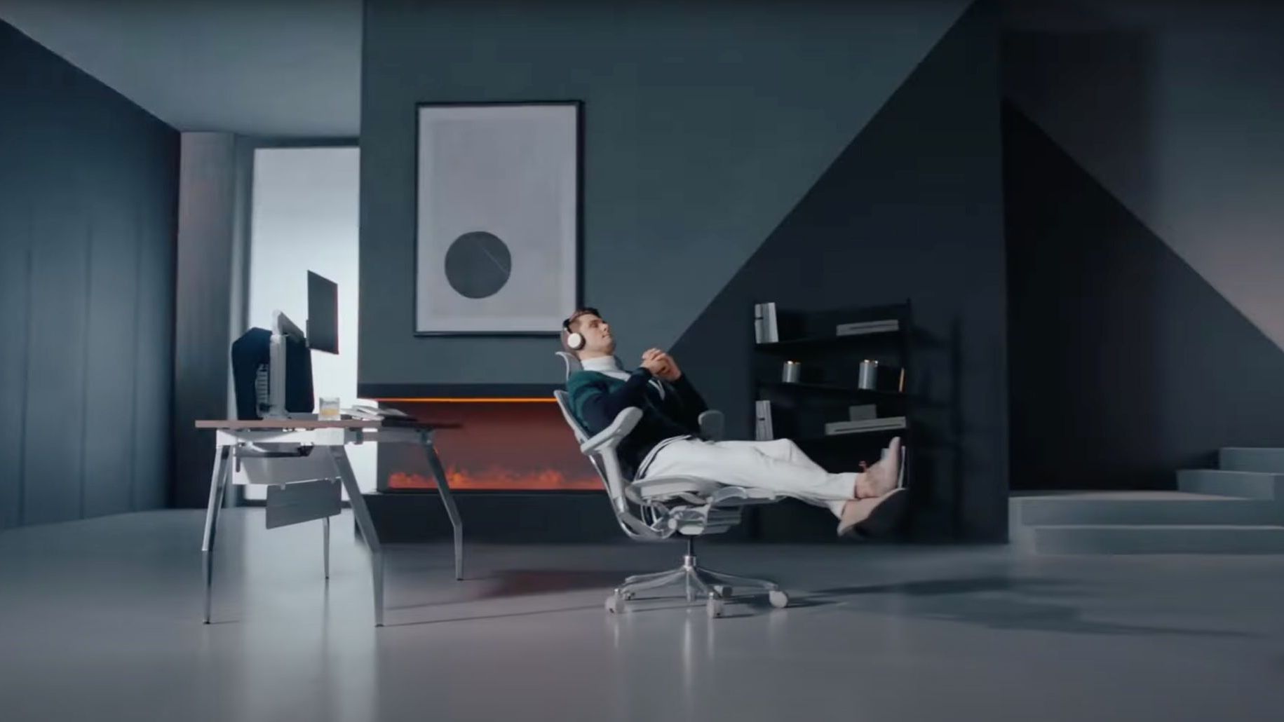 Contemporary grey home office with a stylish man reclining in an Ergohuman mesh office chair. The man is wearing earphones and looks relaxed. The perfect chair for creative work.