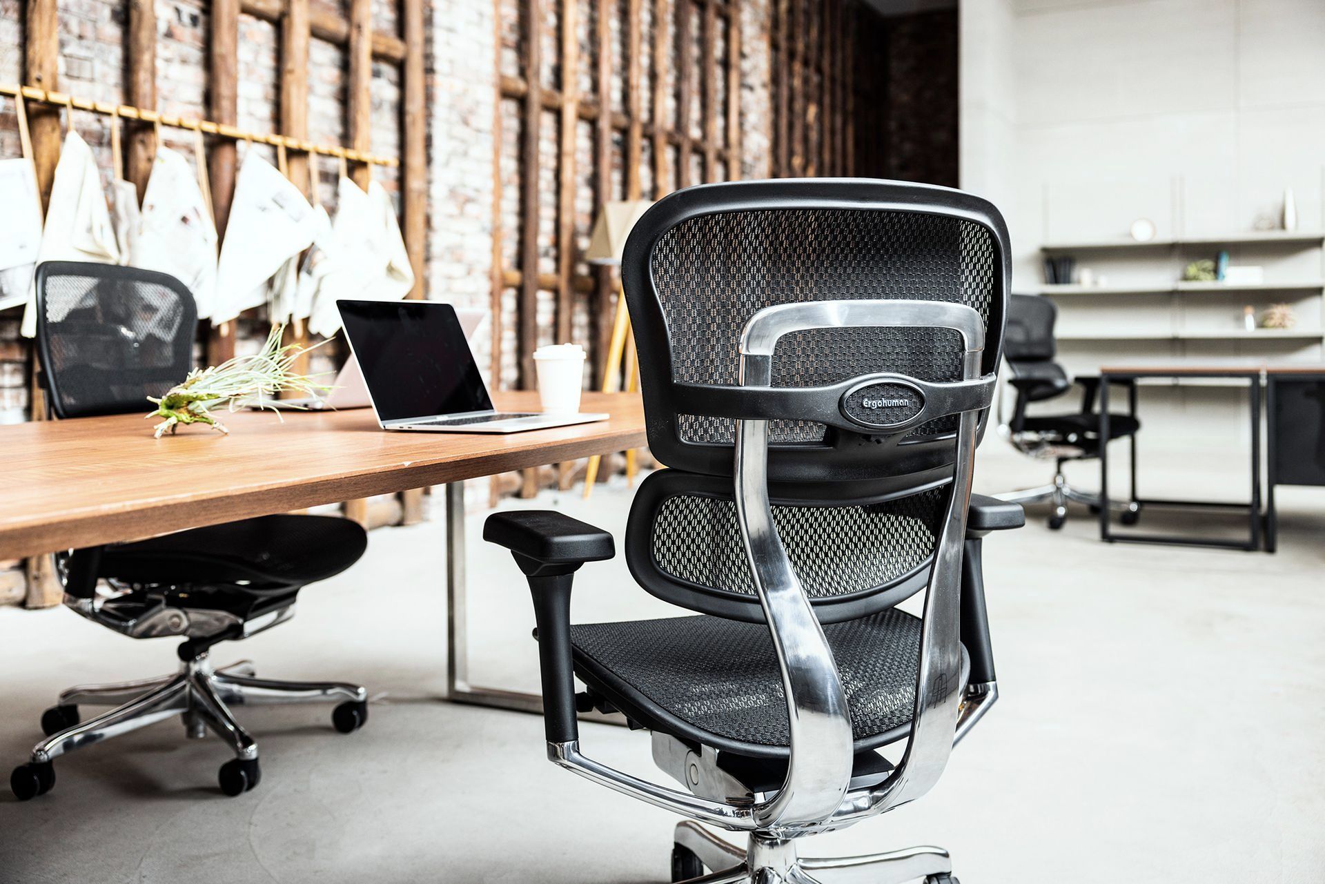 Black Ergohuman chair at a wooden desk with a laptop open
