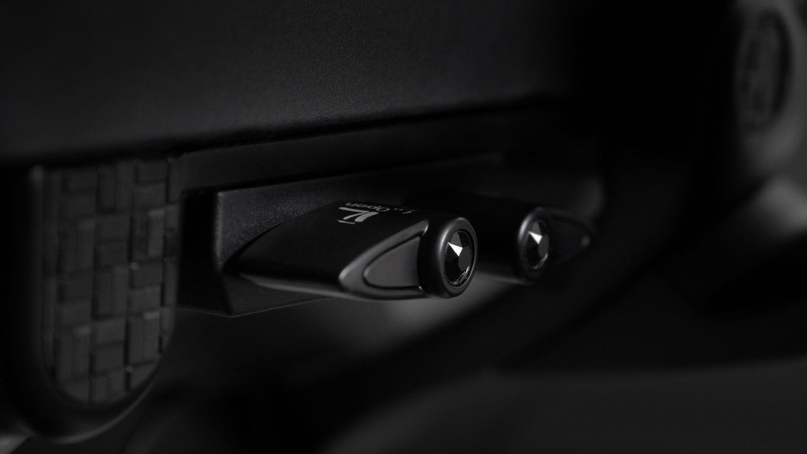 Close up of a mesh gaming chair's levers to control forward seat tilt and recline limiter functions.