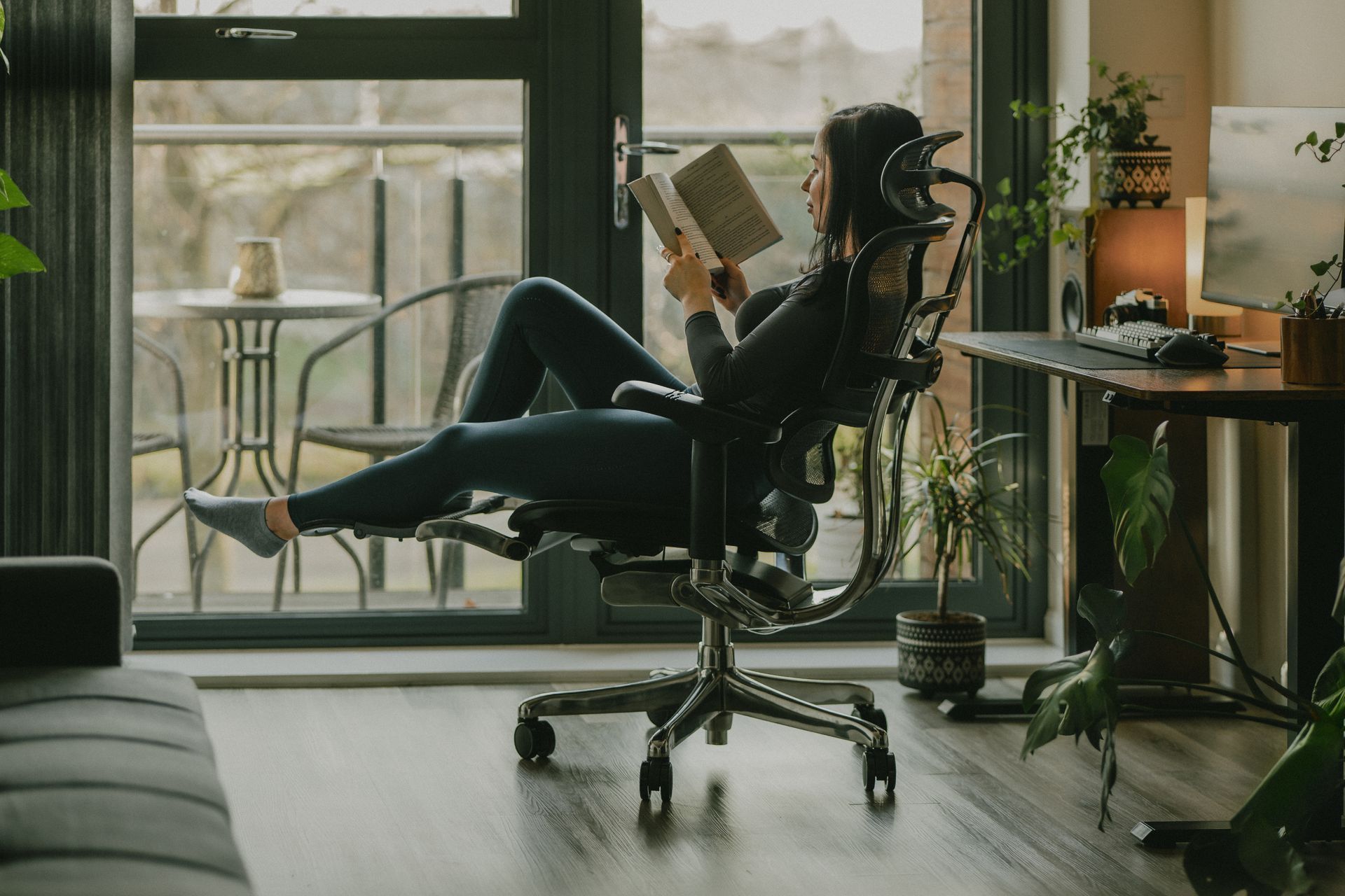 woman reclining in a black ergohuman office chair while reading a book