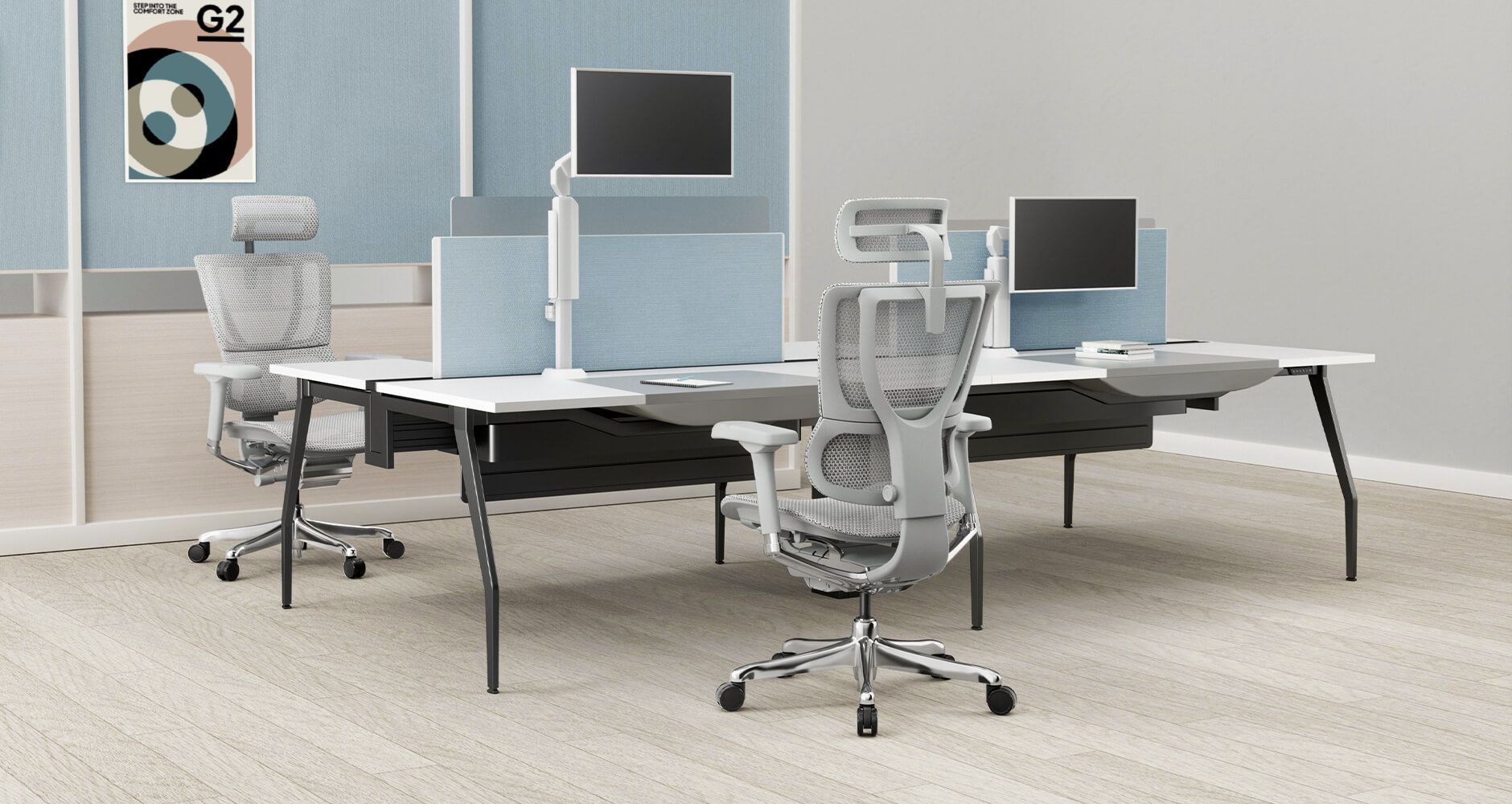 A group of four desks sits in a large office. At two of the desks are the grey Mirus Elite G2 chair. The desks have monitors on a monitor arm so workers can switch between sitting and standing.