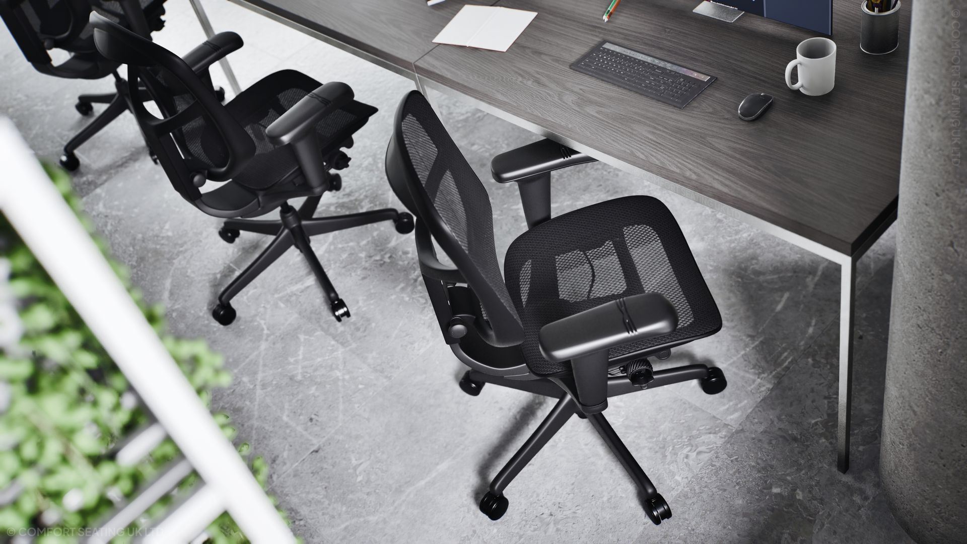 A high view shows Comfort Seating UK's Project Enjoy G2 Enjoy Ultra chair sat along a run of desks in an office. The chair is in a black frame with black mesh.
