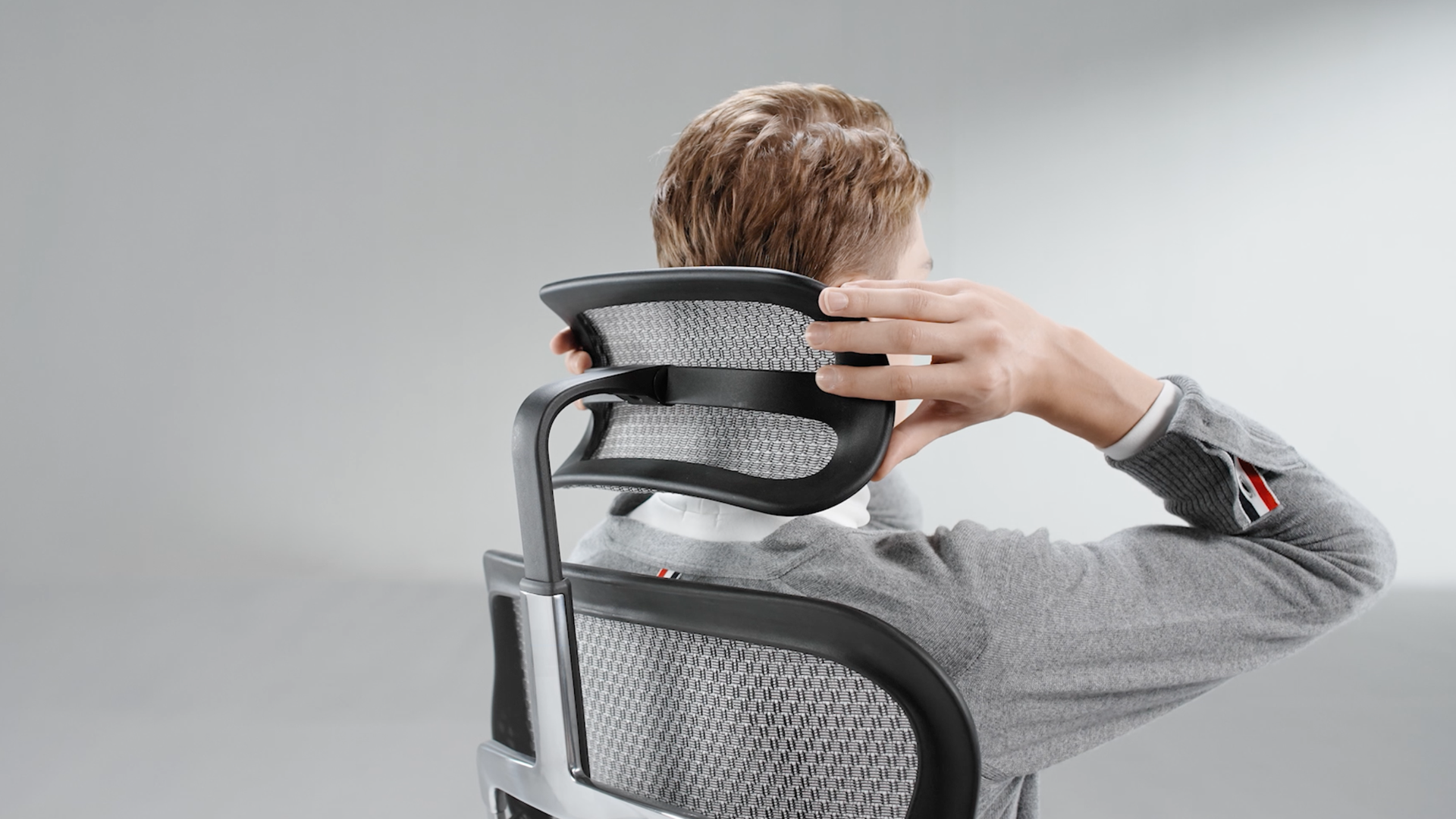 Man reaching back behind him to adjust the headrest on the Ergohuman Elite G2 office chair